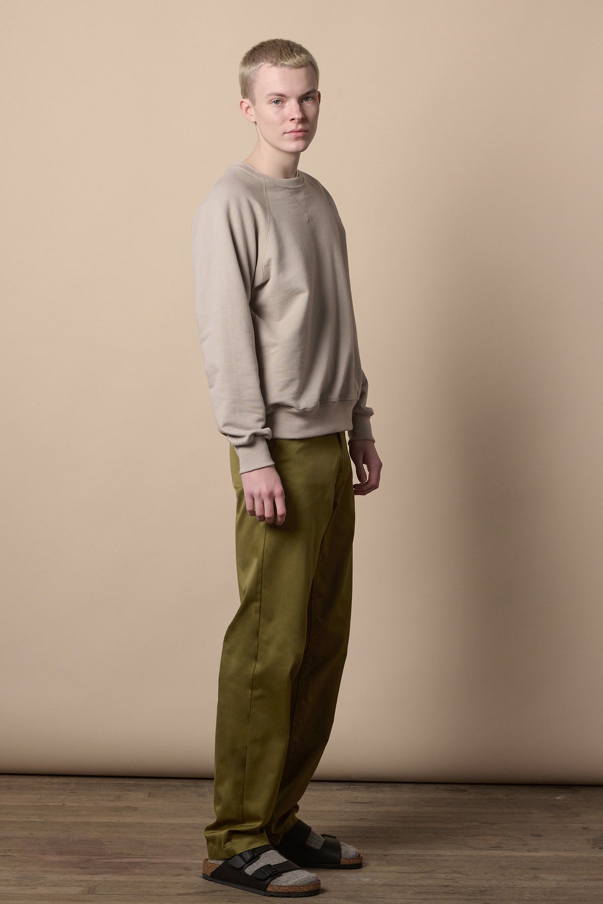 Full body image of white male wearing relaxed chino in moss paired with sweatshirt in stone