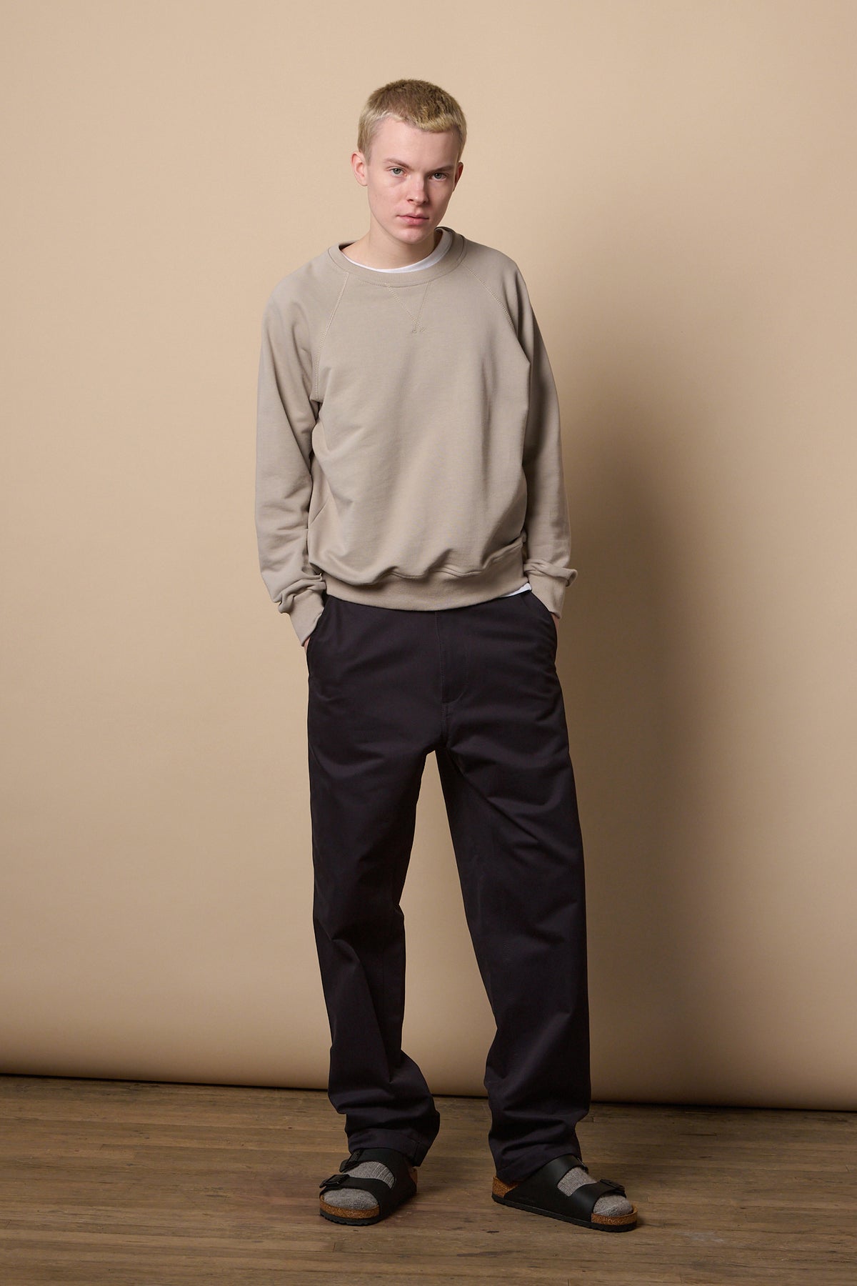 Full body shot of white male wearing men's relaxed chino in navy paired with men's raglan sweatshirt in stone.