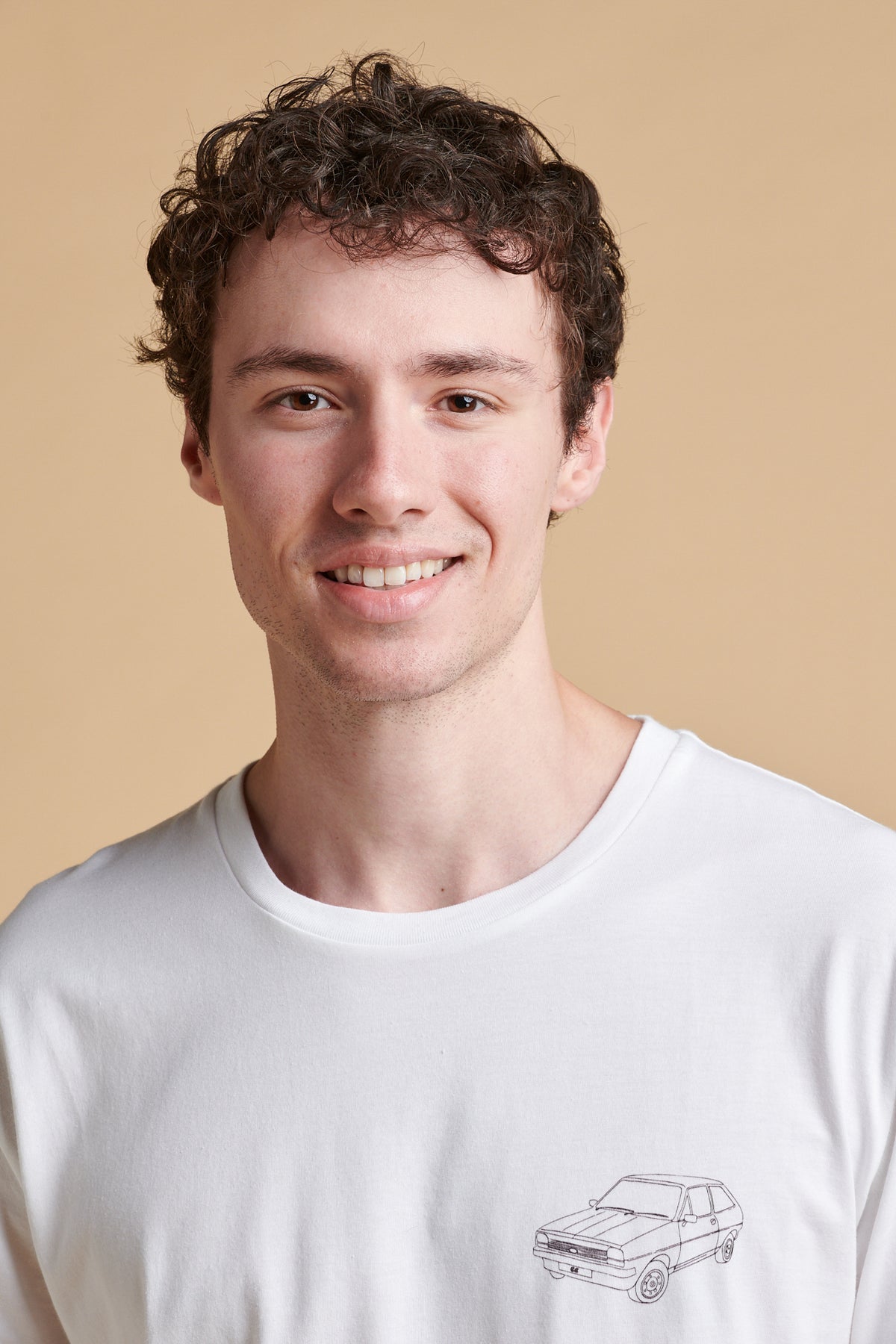 Portrait of male wearing short sleeve graphic t shirt in white with Fiesta car print.