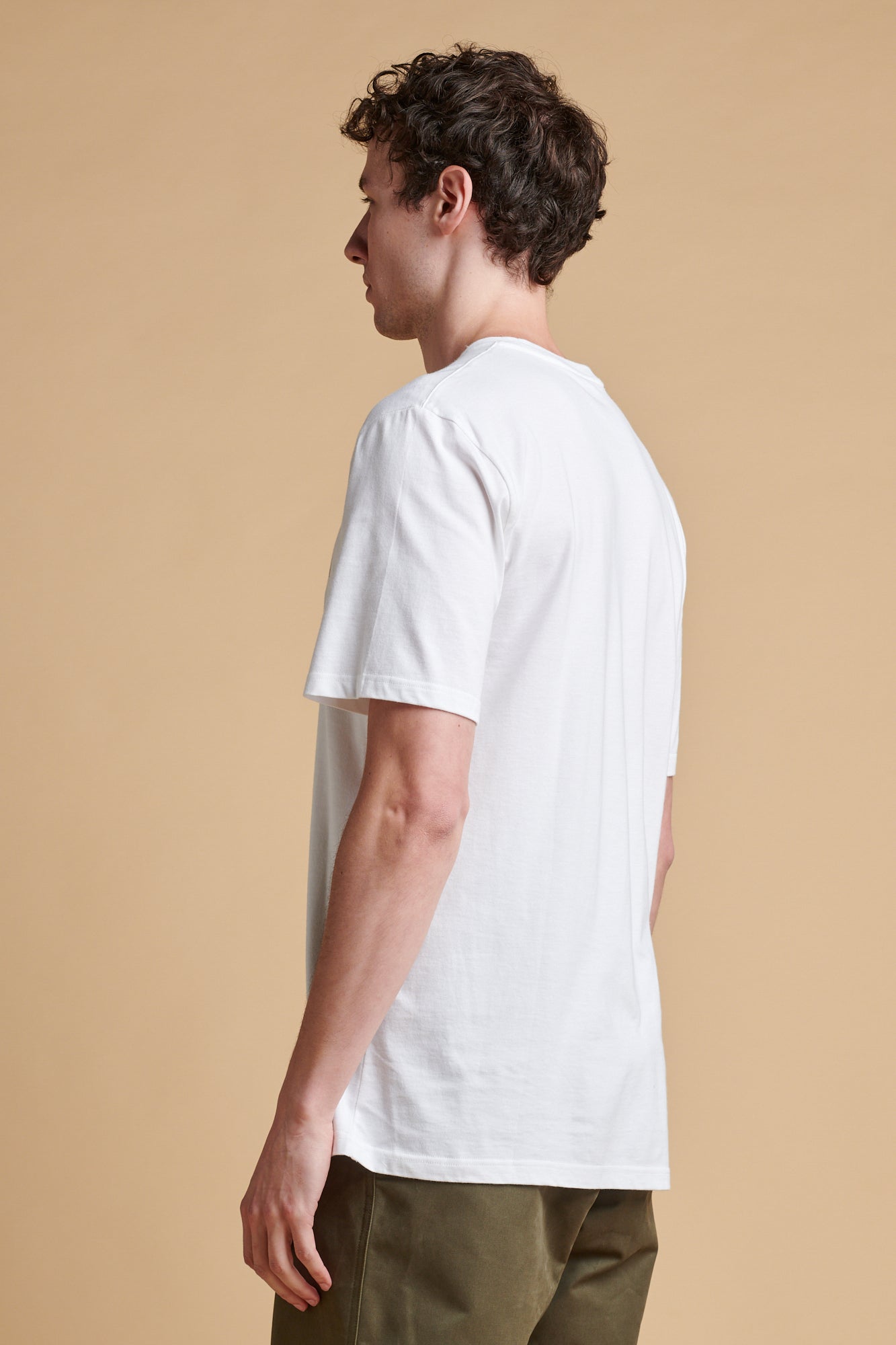 The back of male wearing short sleeve graphic t shirt in white.