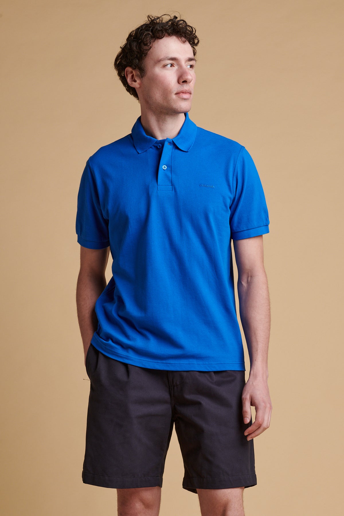 Thigh up front of male wearing short sleeve polo shirt in cobalt.