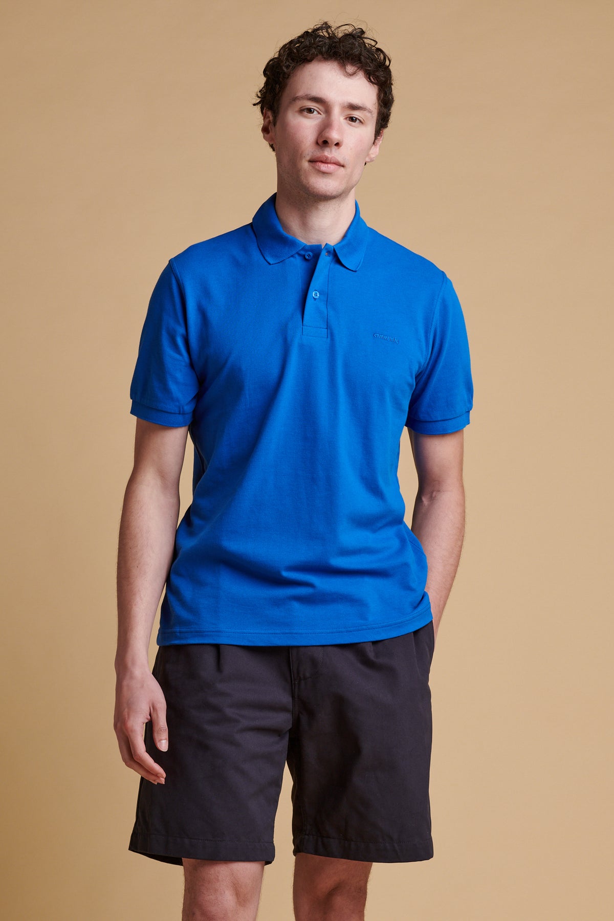 Thigh up front of male wearing short sleeve polo shirt in cobalt.