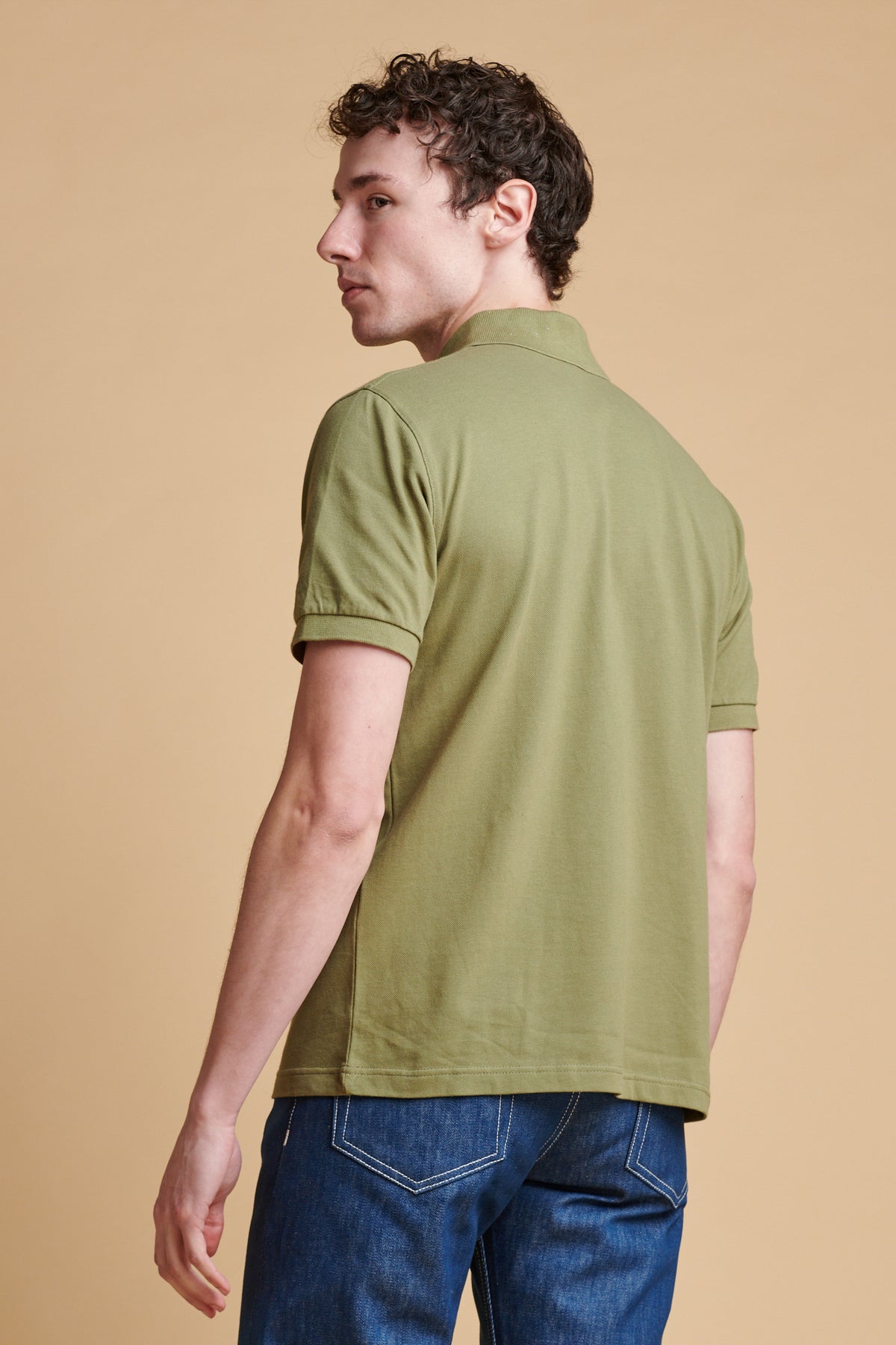 The back of male wearing short sleeve polo shirt in light olive.