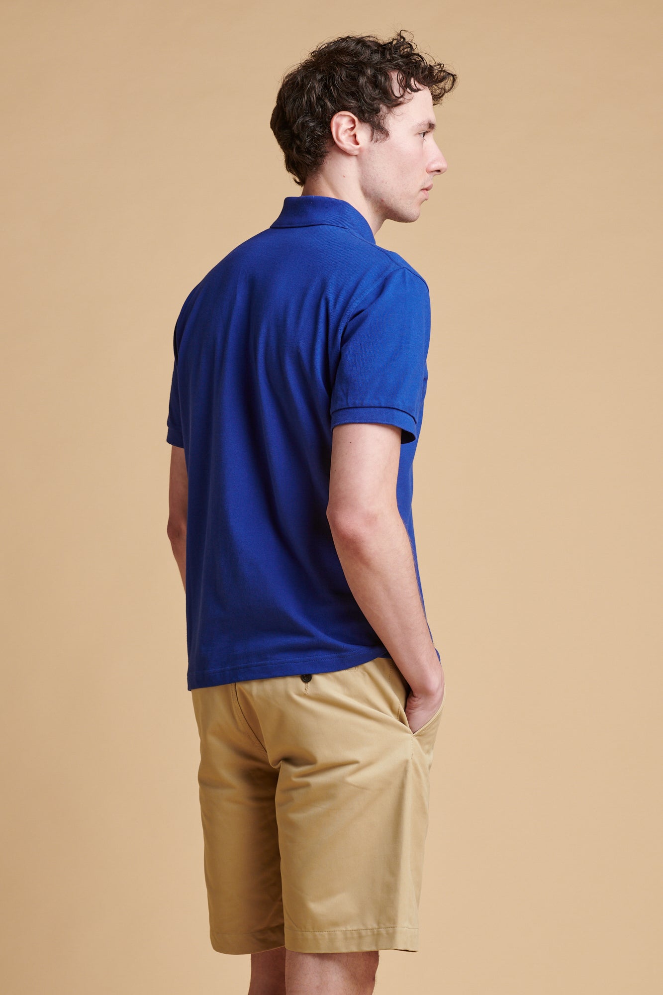 The back of male wearing short sleeve polo shirt in royal blue.