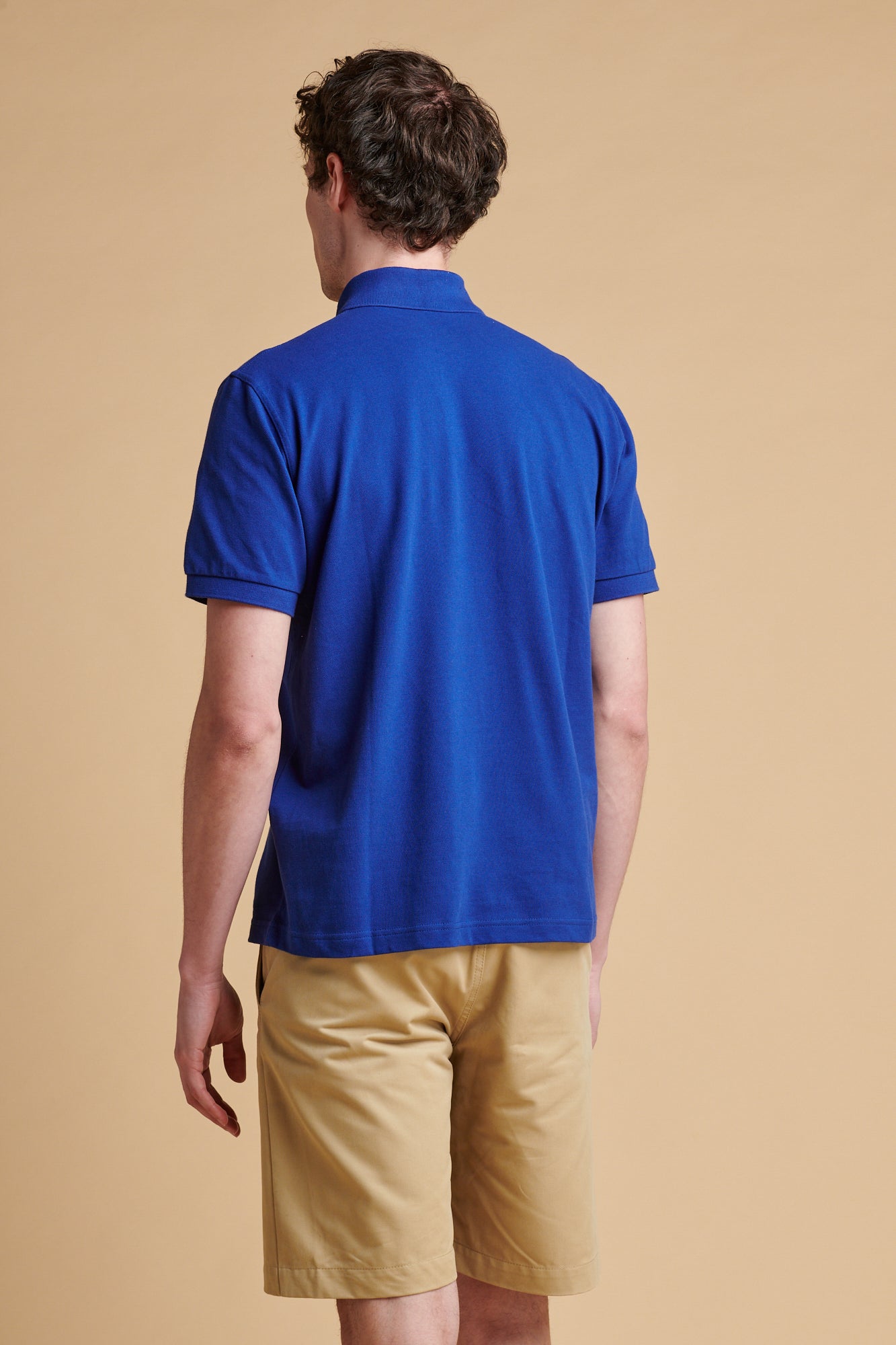 The back of male wearing short sleeve polo shirt in royal blue.