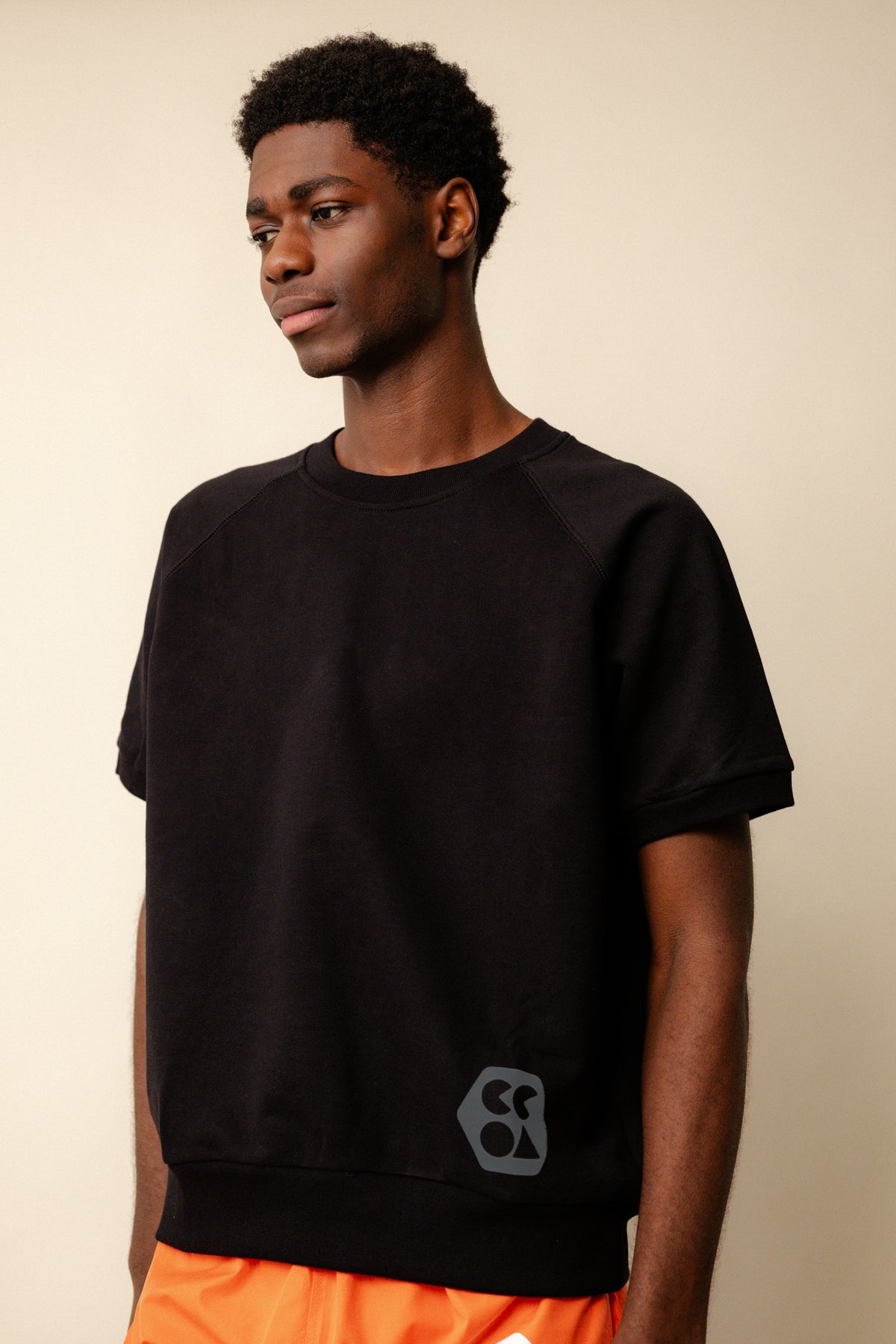 Black male wearing short sleeve raglan training top plastic free in black with CCOA logo