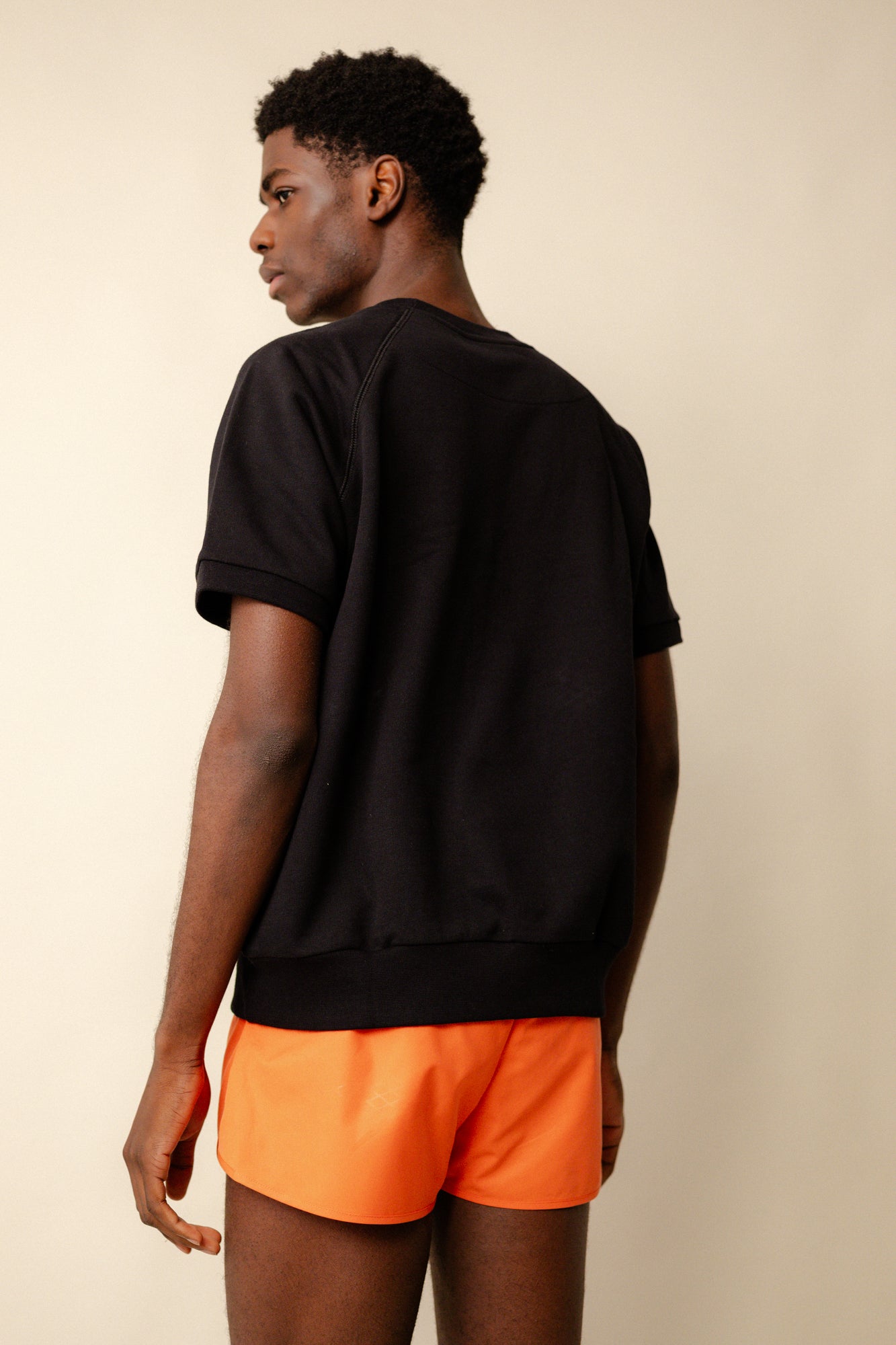 Back of black male wearing short sleeve raglan training top plastic free in black with CCOA logo