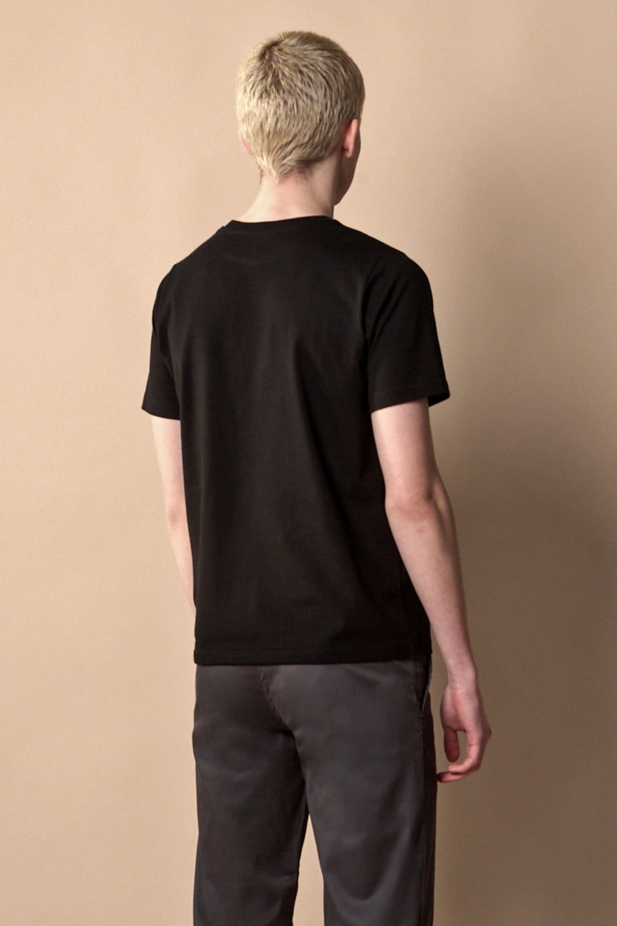 Thigh up back of male with short blond hair wearing short sleeve t-shirt in black.