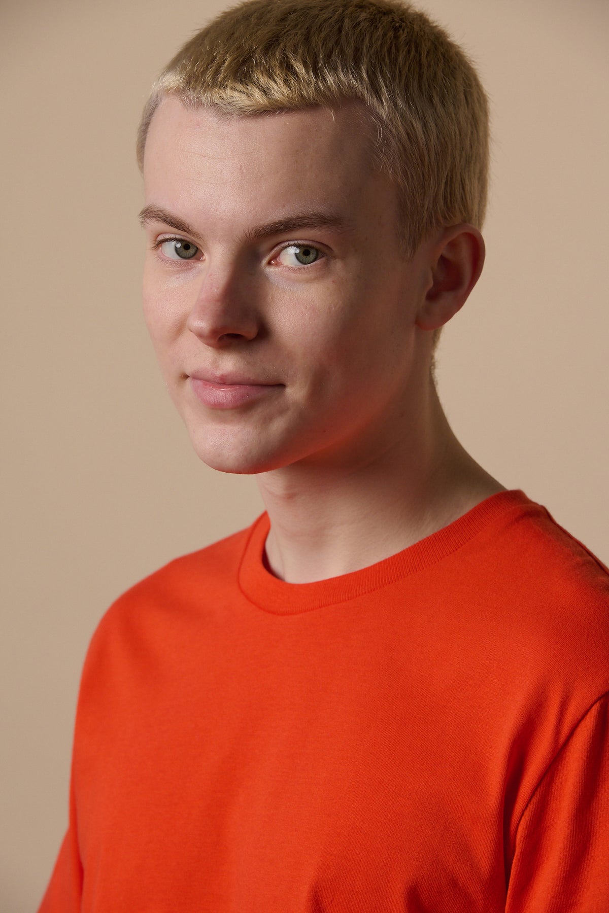 Portrait of white male with short blonde hair wearing short sleeve t shirt in flame red