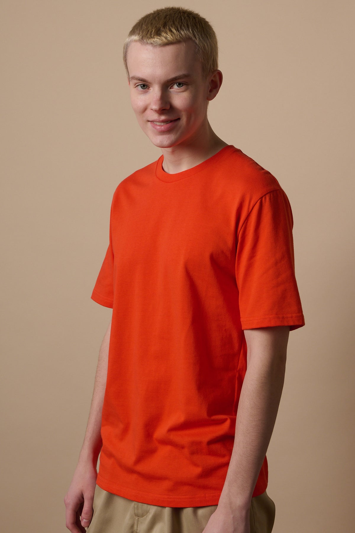 Hip up image of smiley male wearing short sleeve t shirt in flame red