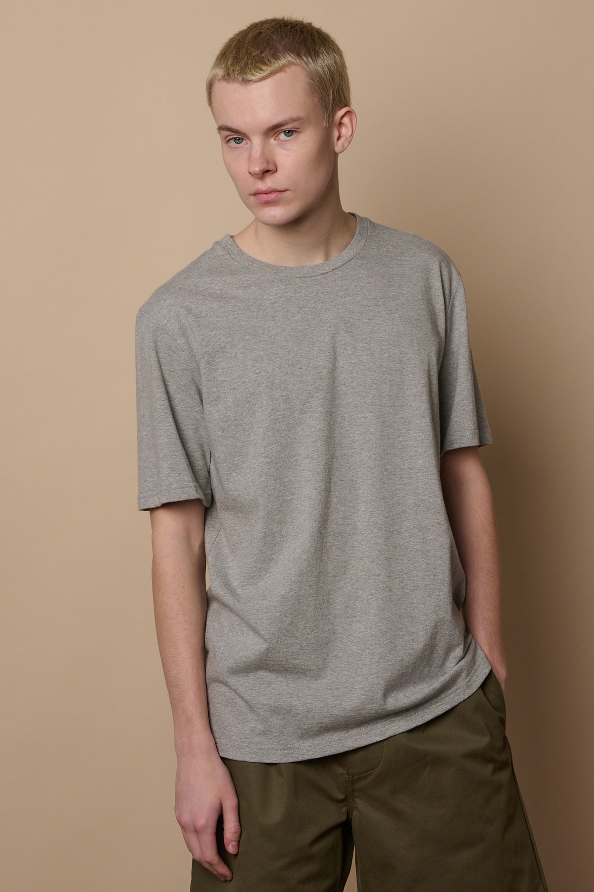 Thigh up image of male wearing short sleeve t shirt in grey paired with shorts in olive
