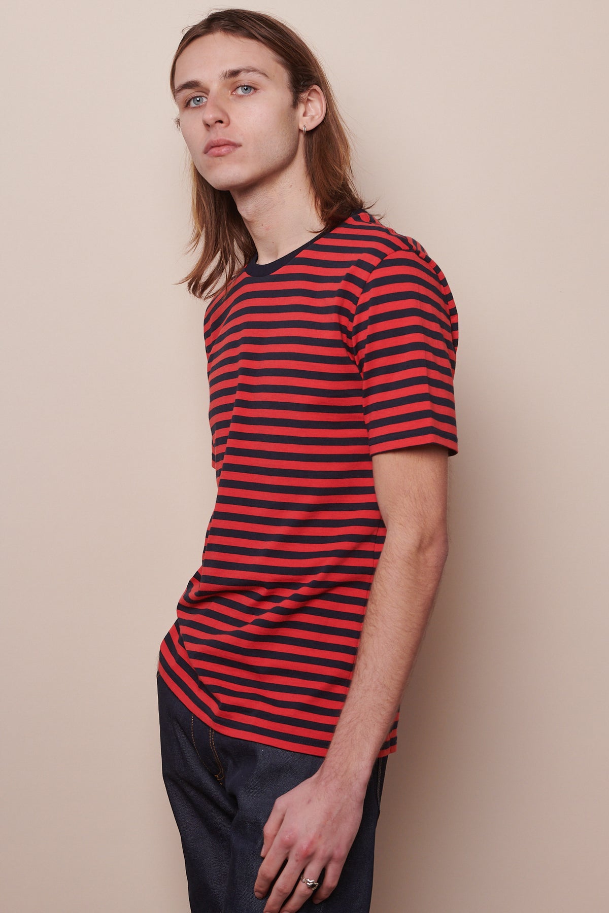 thigh up image of male from the side wearing short sleeve t shirt in navy red stripes
