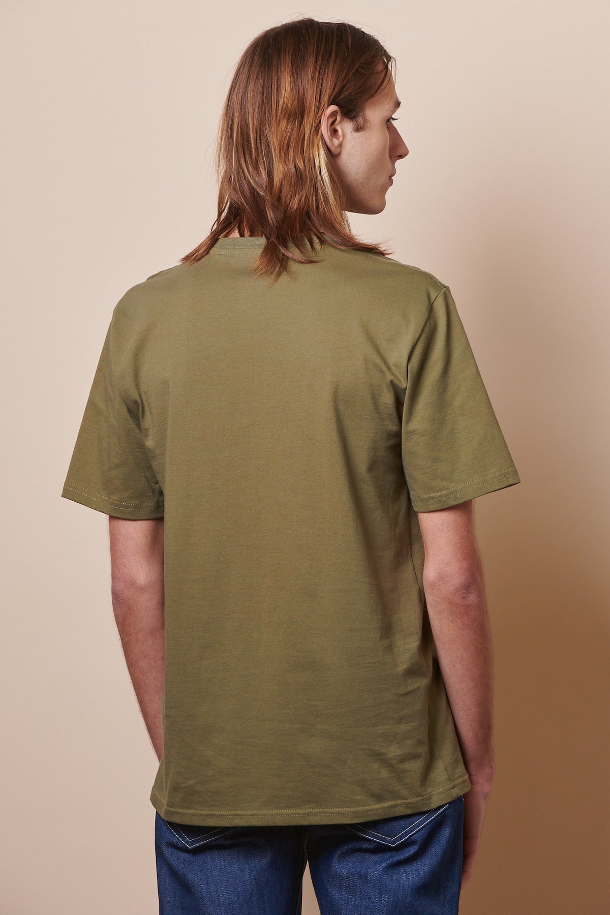 
            The back of male wearing short sleeve t shirt in olive with jeans