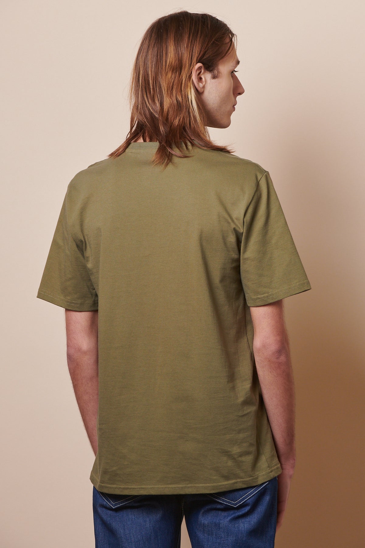 The back of male wearing short sleeve t shirt in olive with jeans