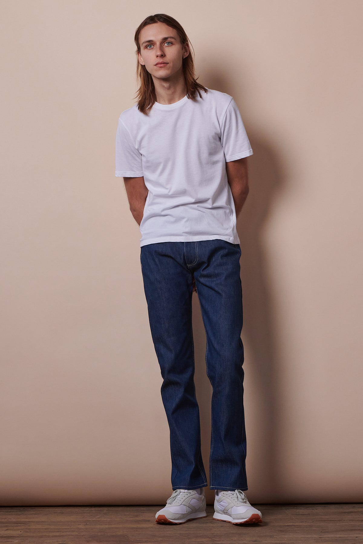 
            Male wearing short sleeve t shirt in white paired with blue jeans.
