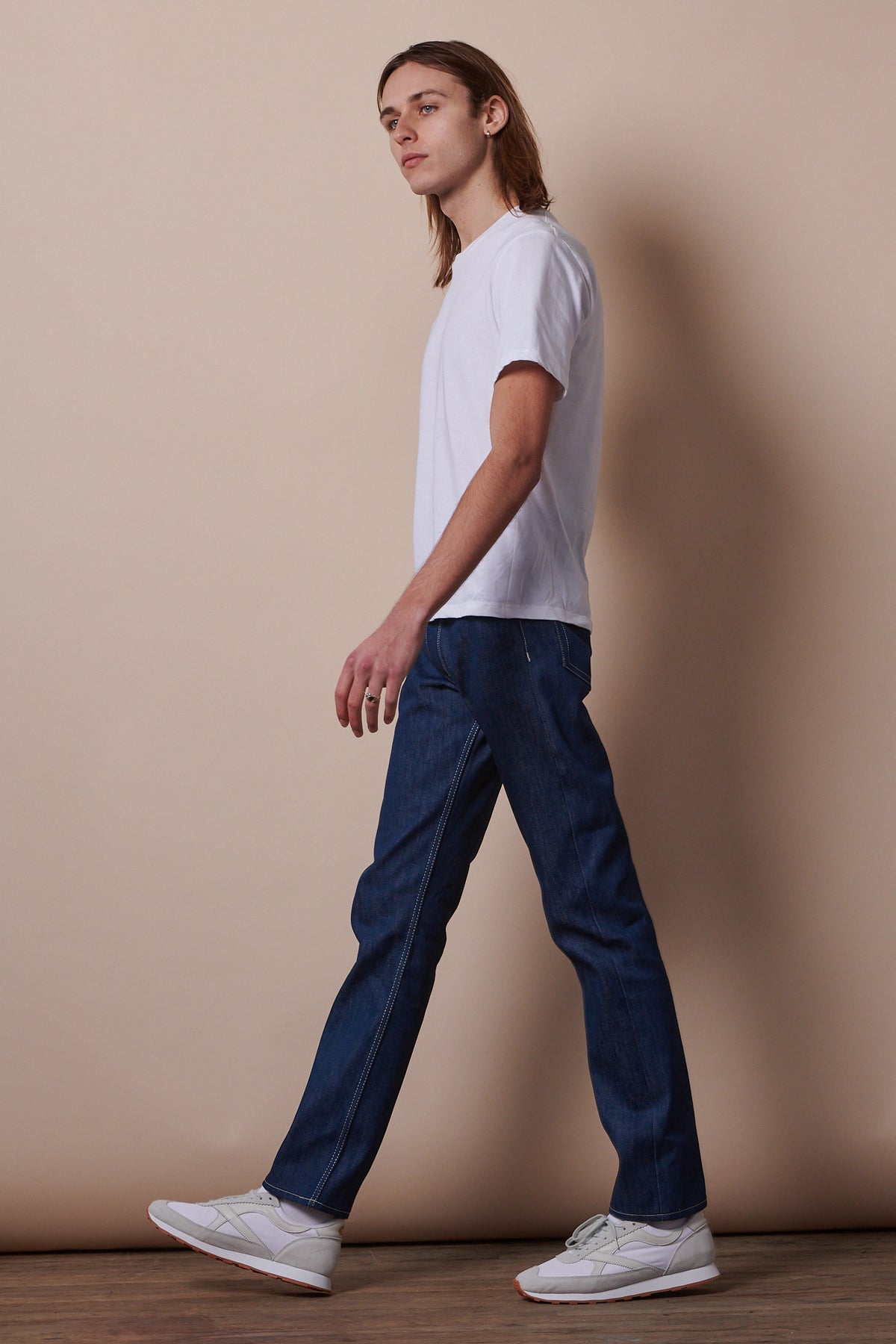 
            Side of male mid walk wearing short sleeve t shirt in white with blue jeans