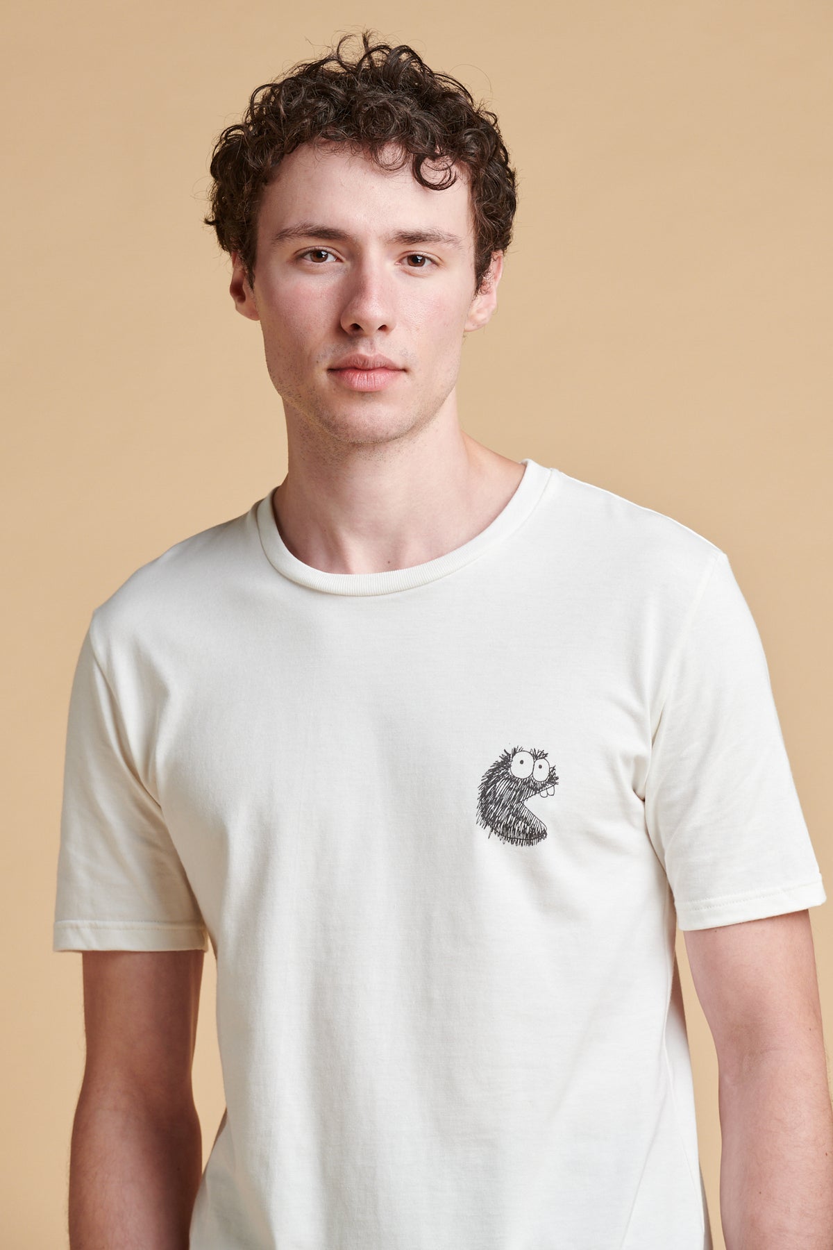 Man wearing a white t-shirt with a logo on a beige background
