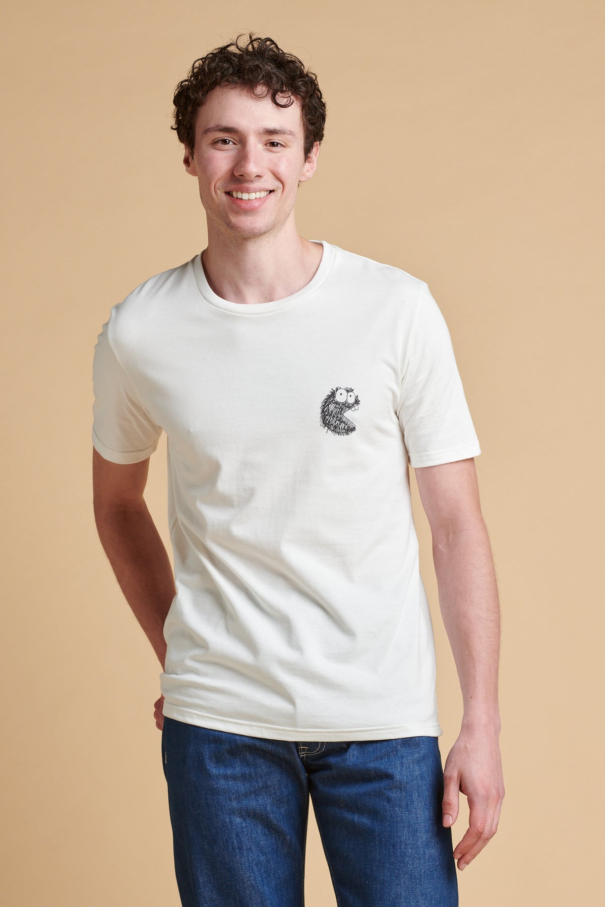 Man wearing a white t-shirt with a small graphic on a beige background