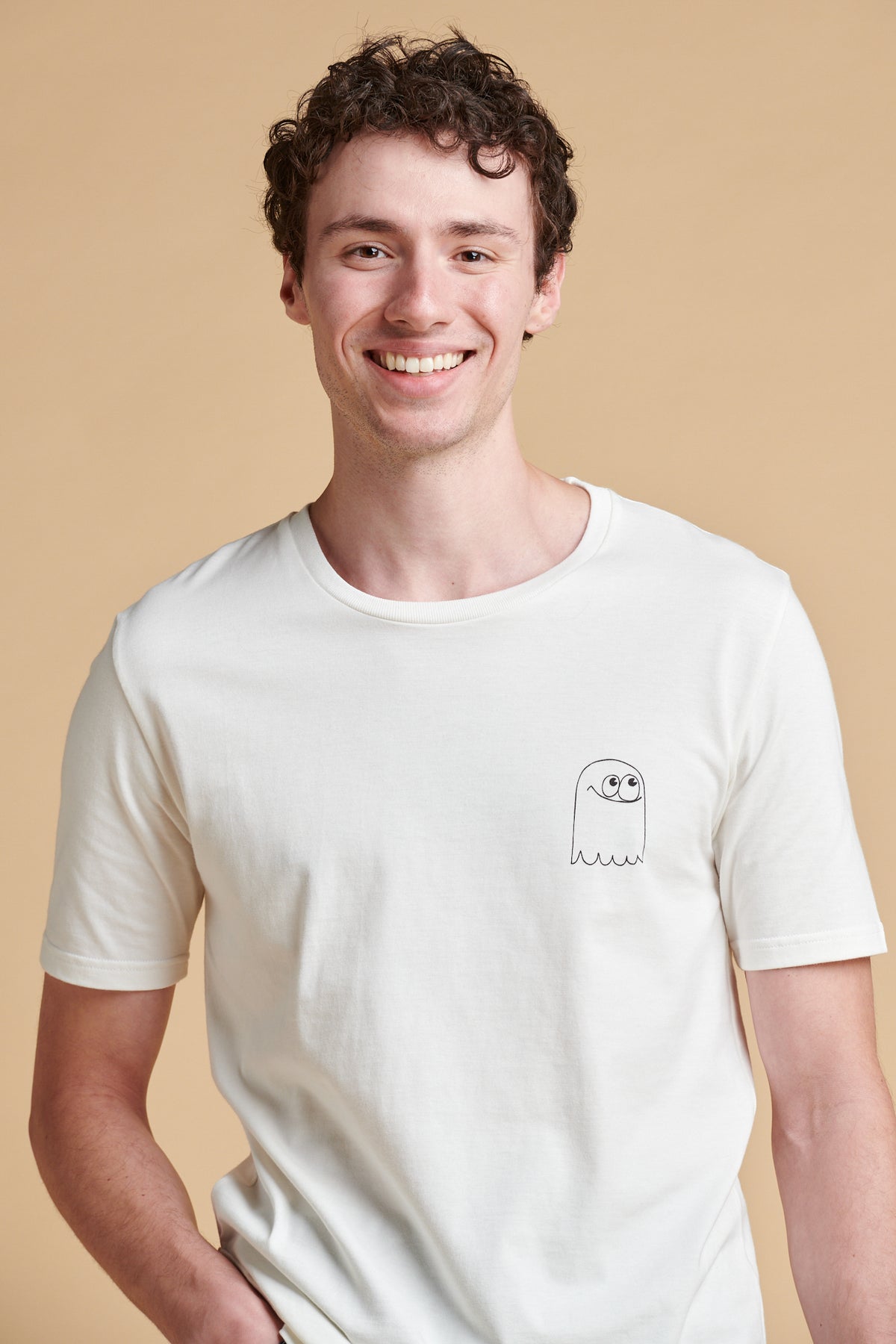 Person wearing a white t-shirt with a small graphic on a beige background