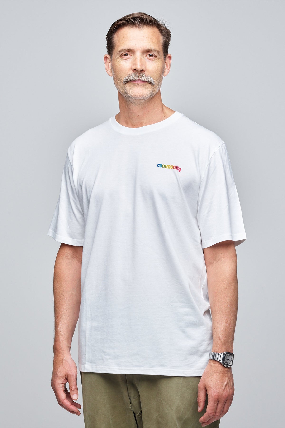 
            Community Clothing founder, Patrick Grant, smiling and wearing a white short sleeve t-shirt with branding on the chest.