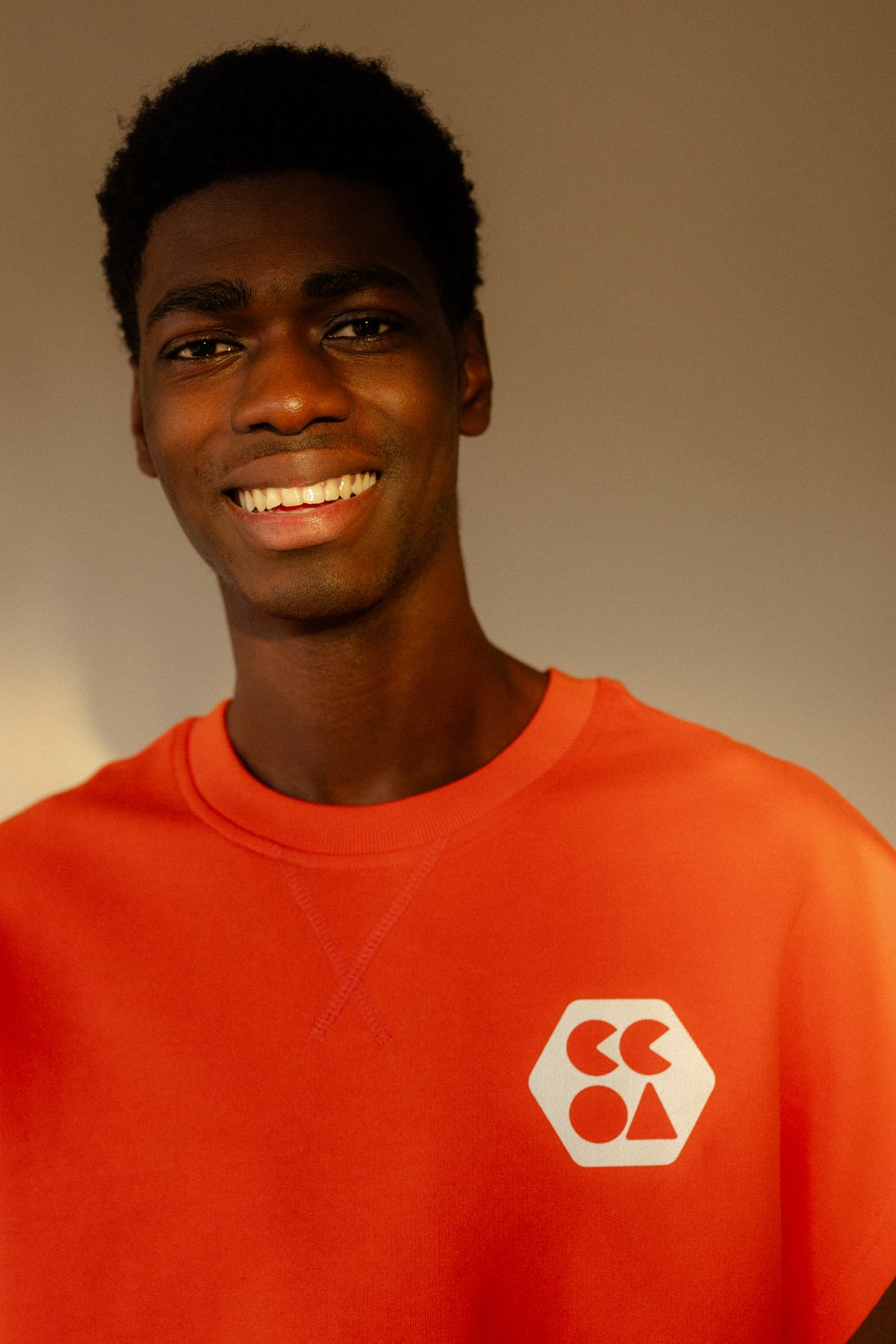 Smiley male wearing sleeveless sweatshirt plastic free in flame red with white CCOA logo
