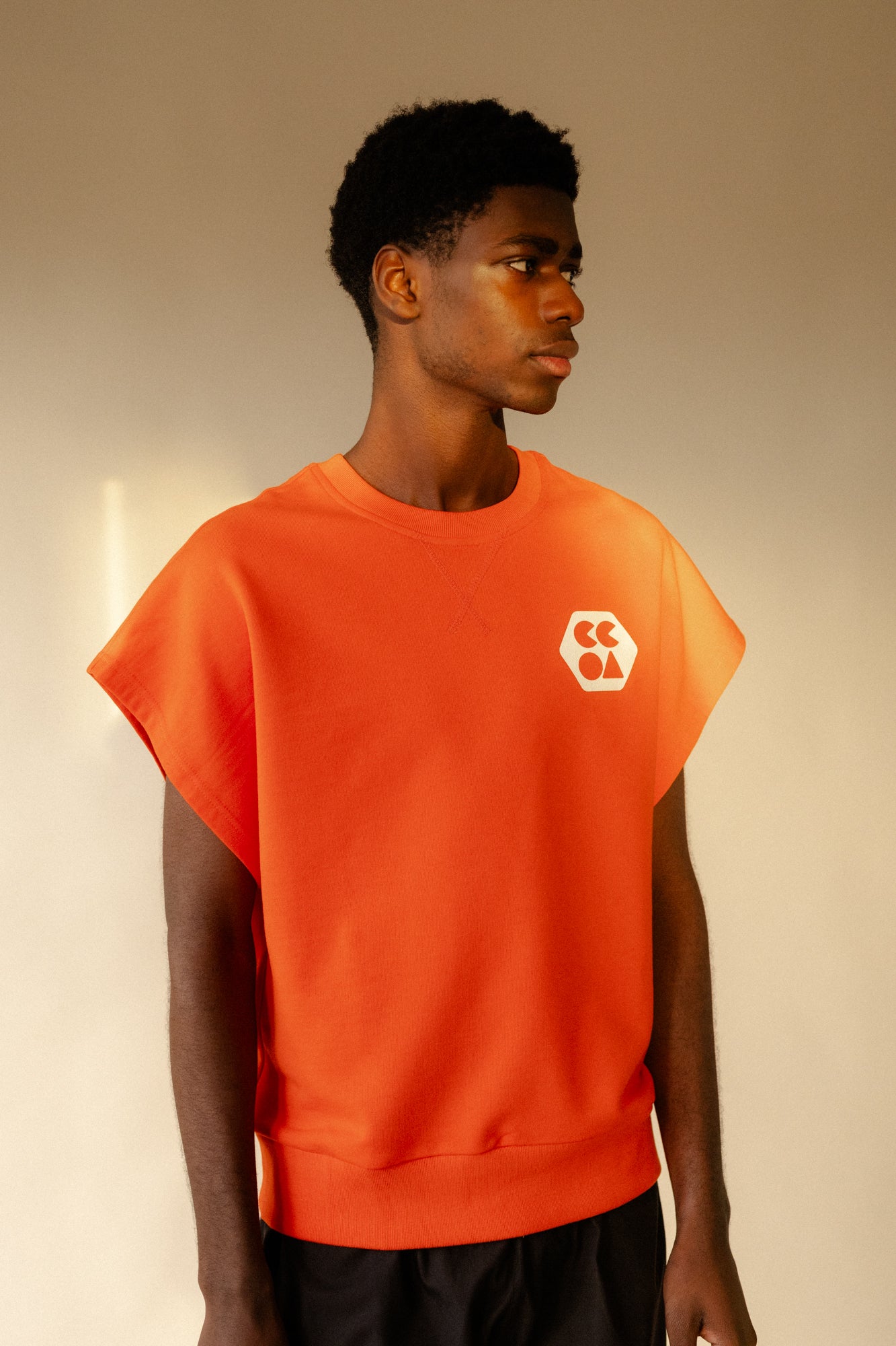 thigh up image of male wearing sleeveless sweatshirt plastic free in flame red