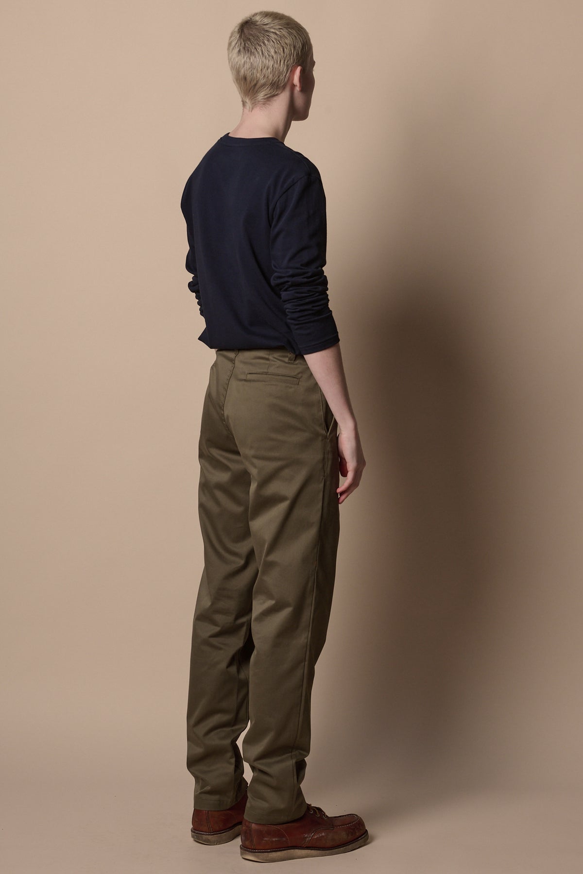 
            Back of male wearing slim chino in olive with navy t shirt tucked in