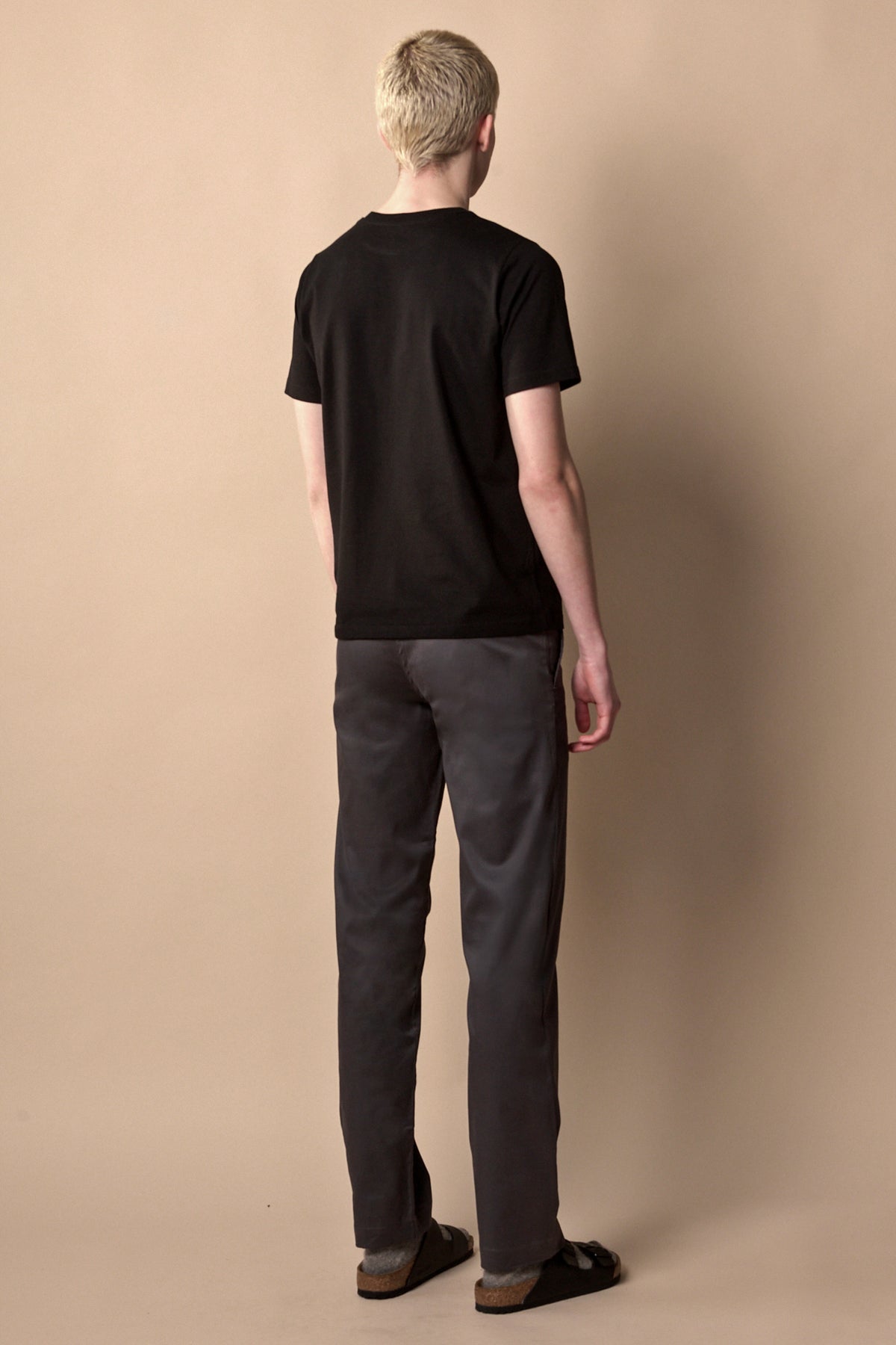 Full body image of the back of men's slim stretch chino in slate grey paired with short sleeve black crew neck t shirt