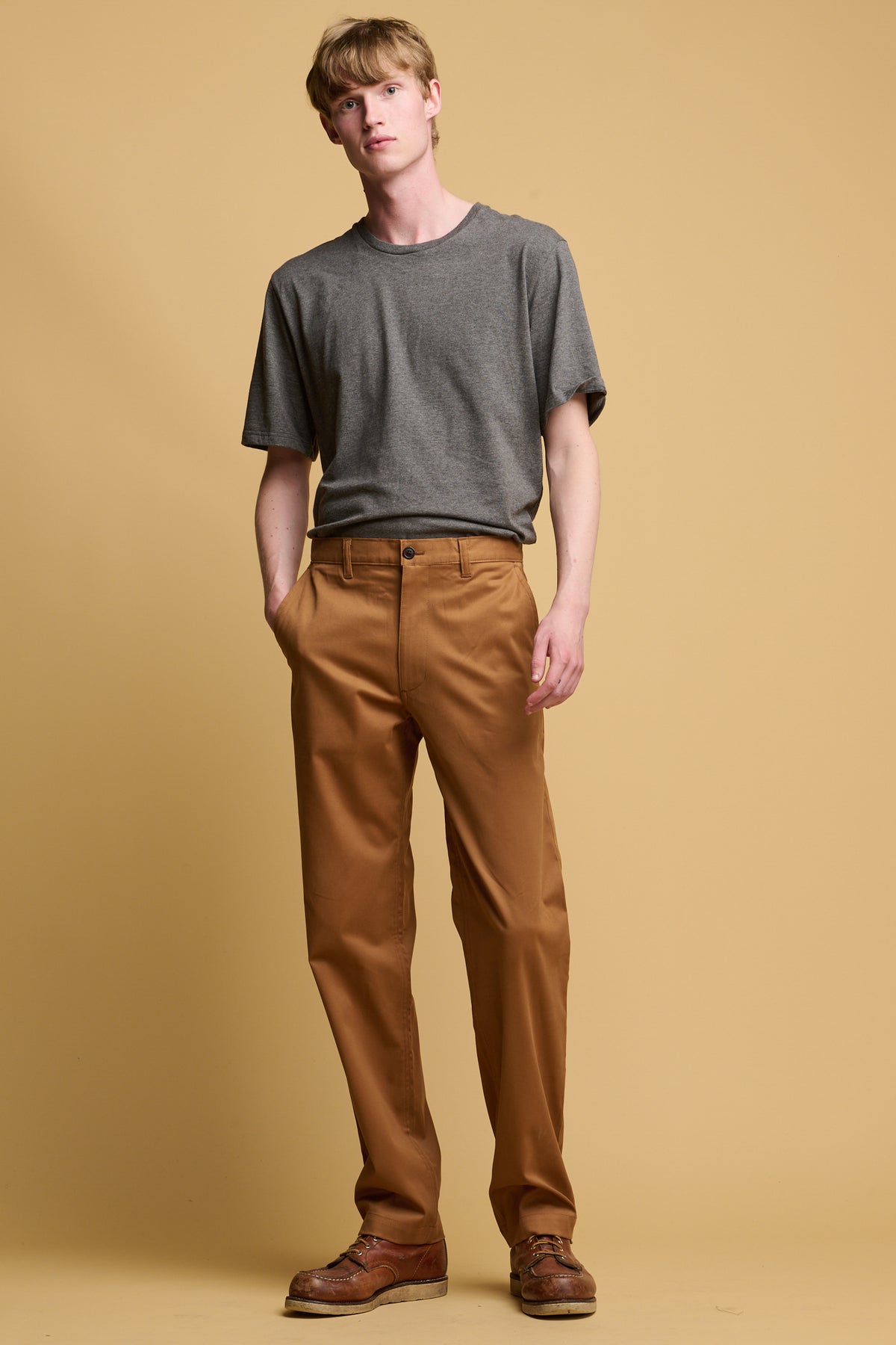 White male wearing slim stretch chino in tobacco paired with short sleeve t shirt in charcoal tucked in