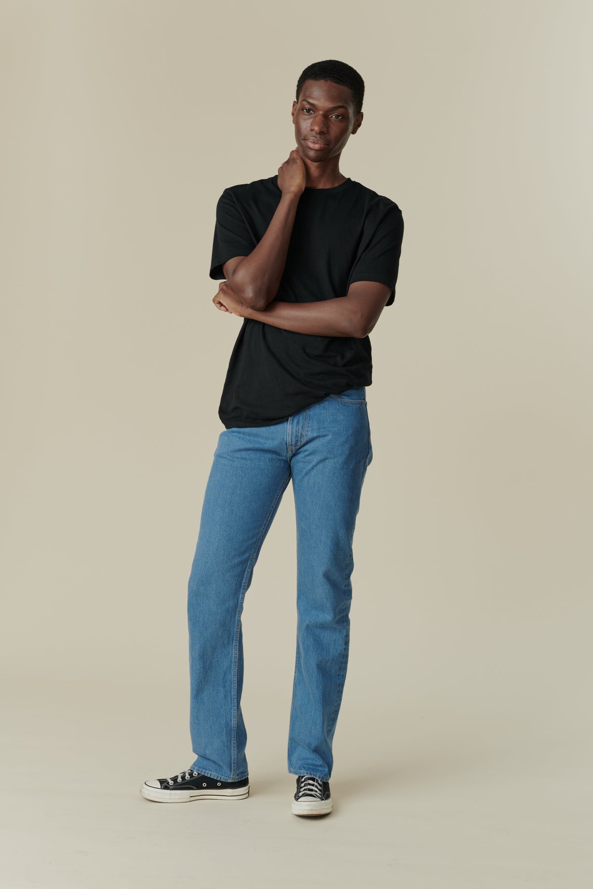 Front full body shot of black male with short dark hair wearing men's straight cut selvedge jeans in fade with a black short sleeve t-shirt.