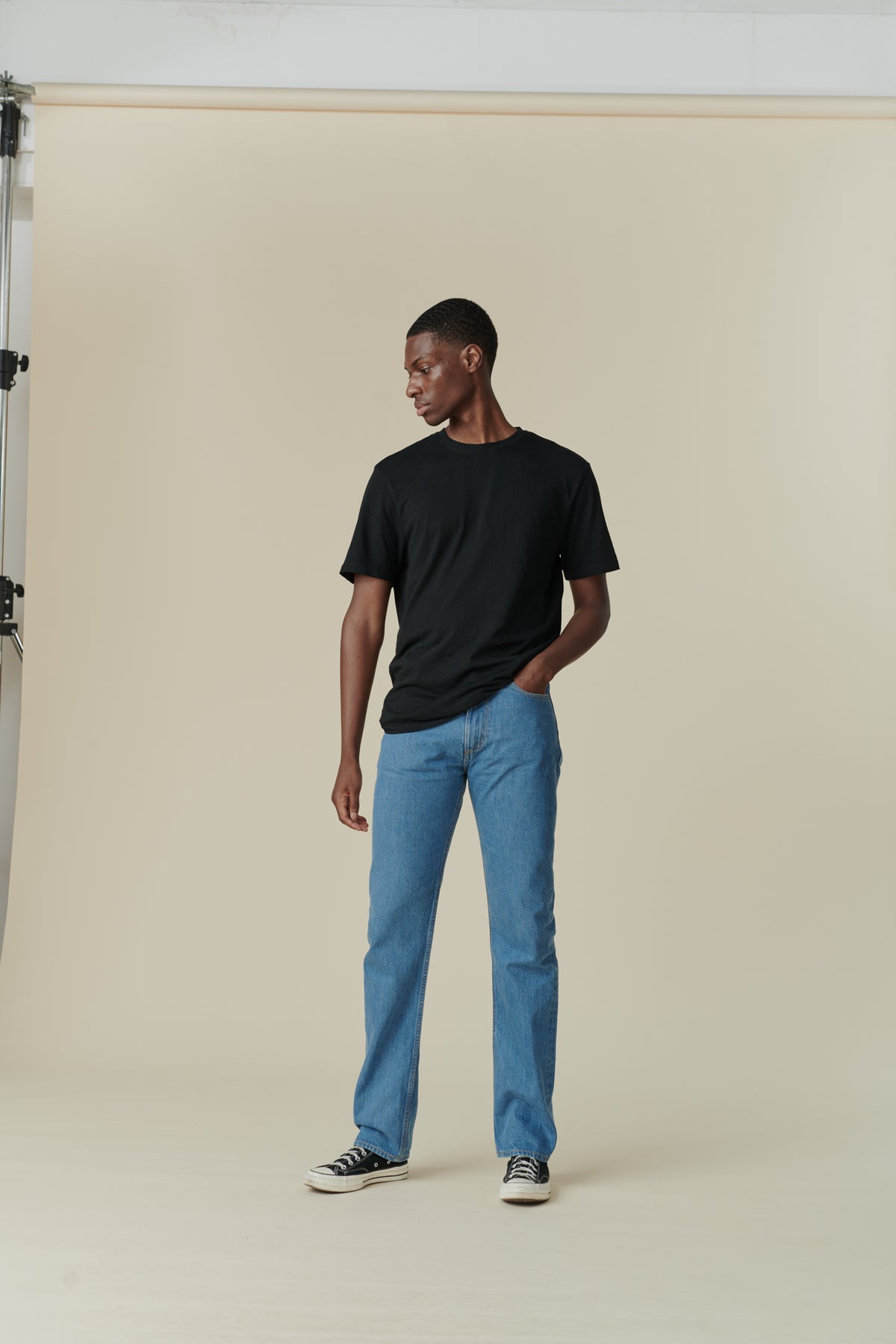 
            Full body shot of front of black male with short dark hair wearing men&#39;s straight cut selvedge jeans in fade with a black short sleeve t-shirt.