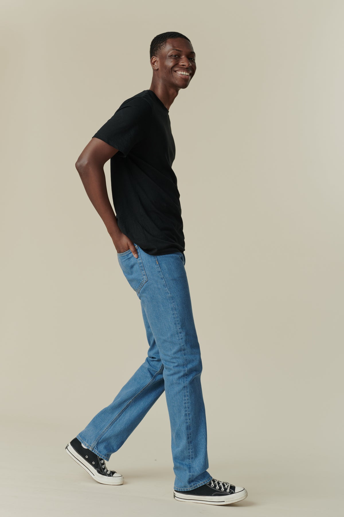 
            Full body side shot of black male with short dark hair, wearing men&#39;s straight cut selvedge jeans in fade with a black short sleeve t-shirt.