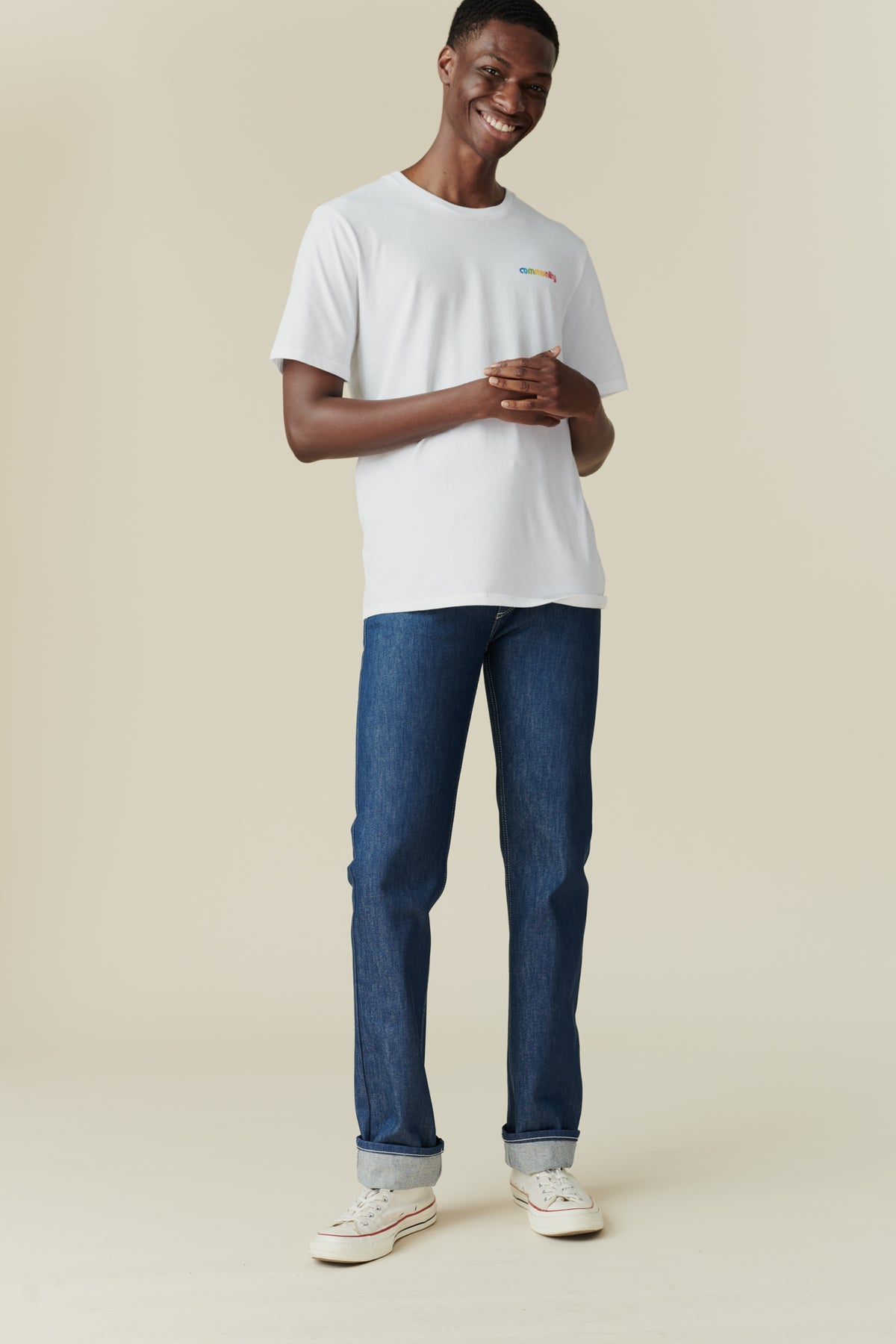 
            Full body front image of black male wearing straight cut jeans in blue, rolled hem. 