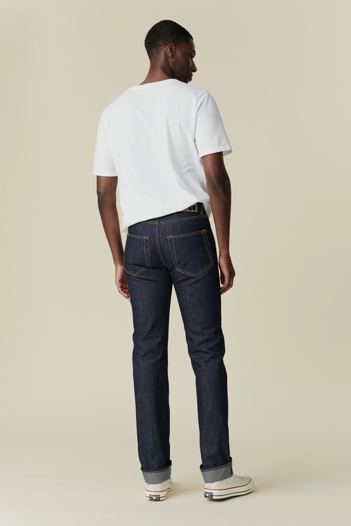 
            Full body image of black male from behind wearing straight leg jeans in indigo