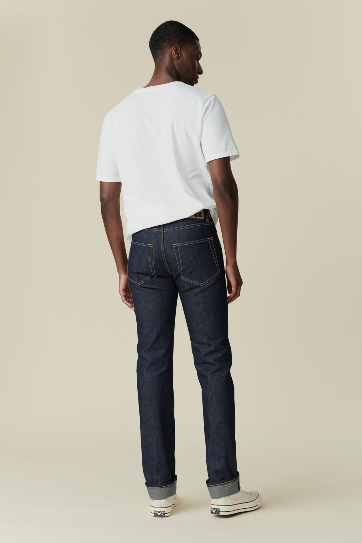 Full body image of black male from behind wearing straight leg jeans in indigo