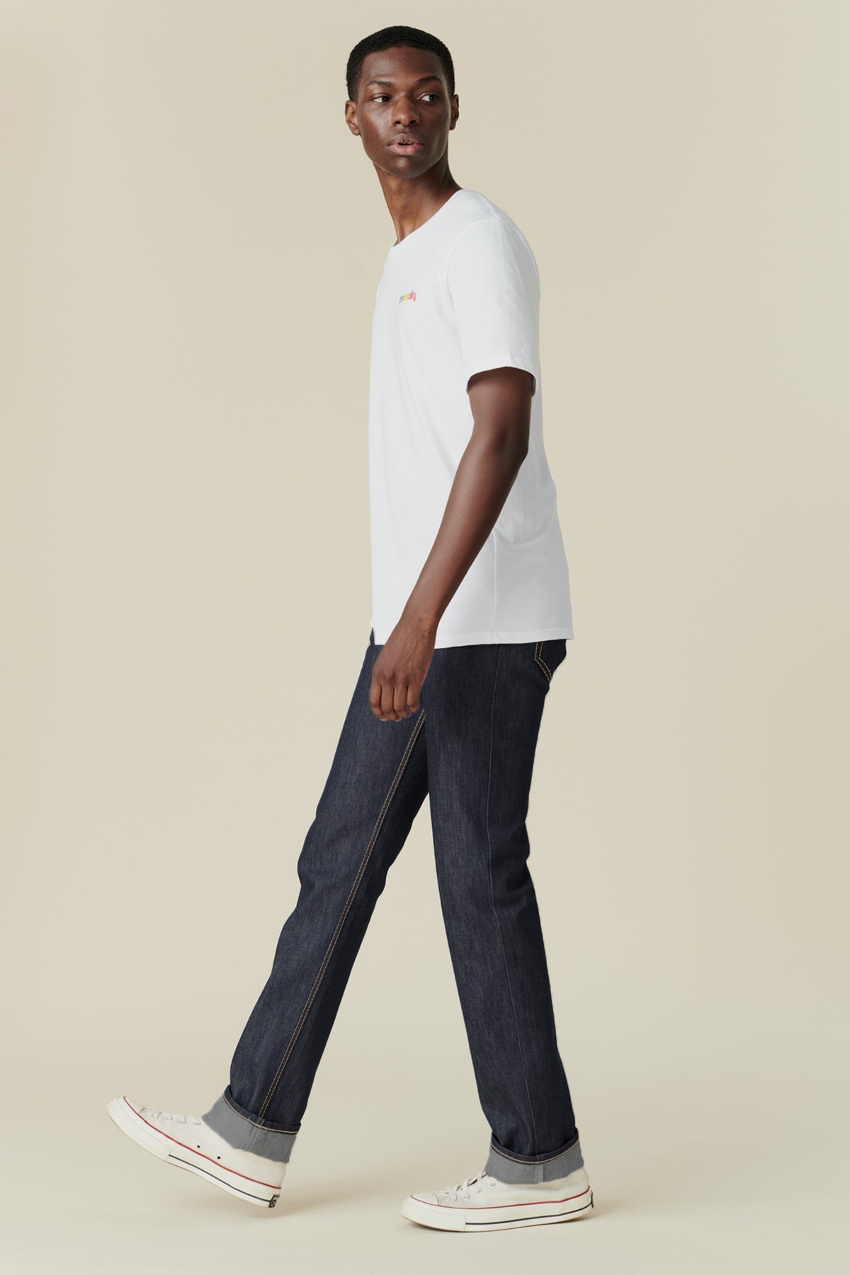 Full body image from the side of black male wearing straight cut jeans in indigo