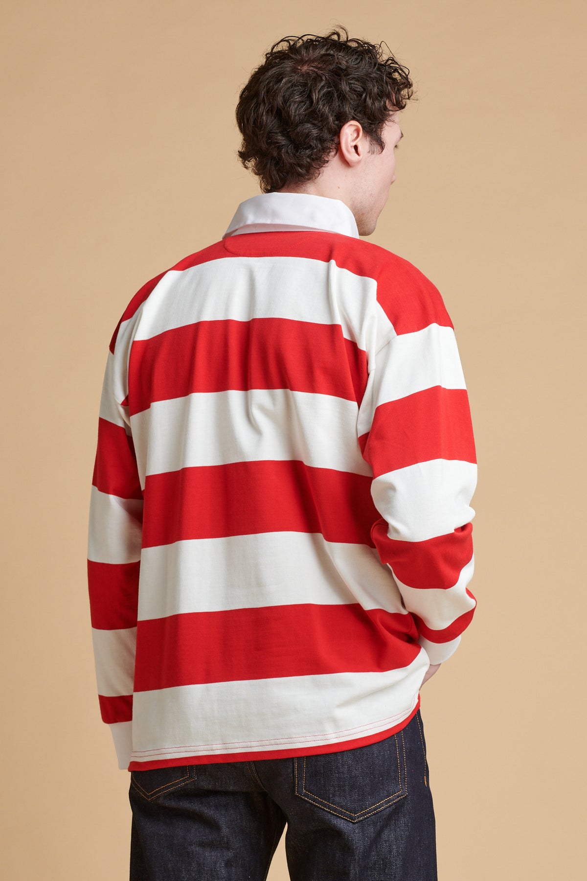 The back of male wearing unisex striped rugby shirt in red and white