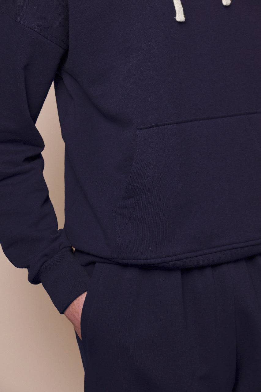 close up of male with hand in front pocket of men's sweatpants in navy paired with matching navy hooded sweatshirt