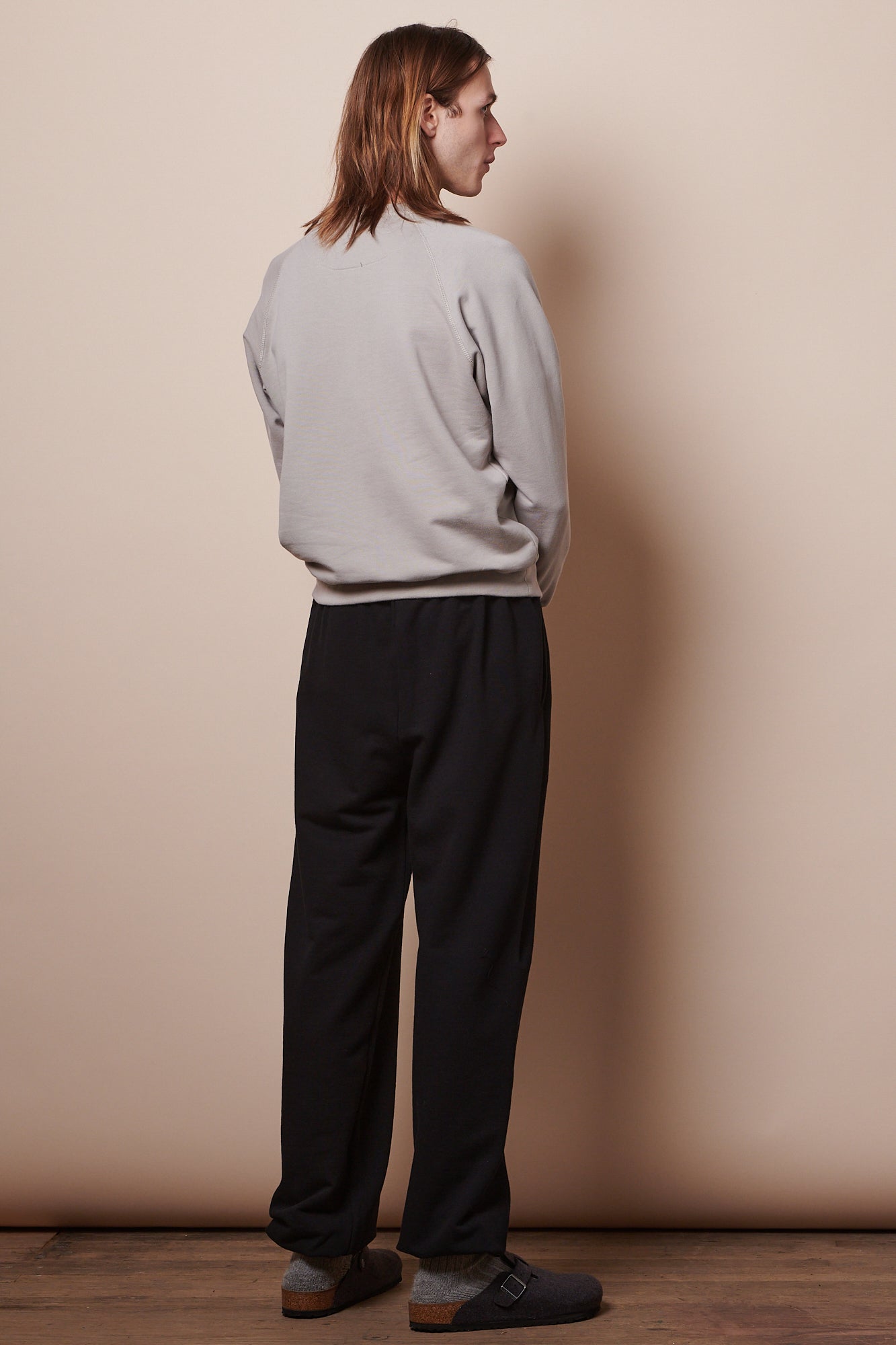 Male wearing sweatpants in black paired with raglan sweatshirt in stone