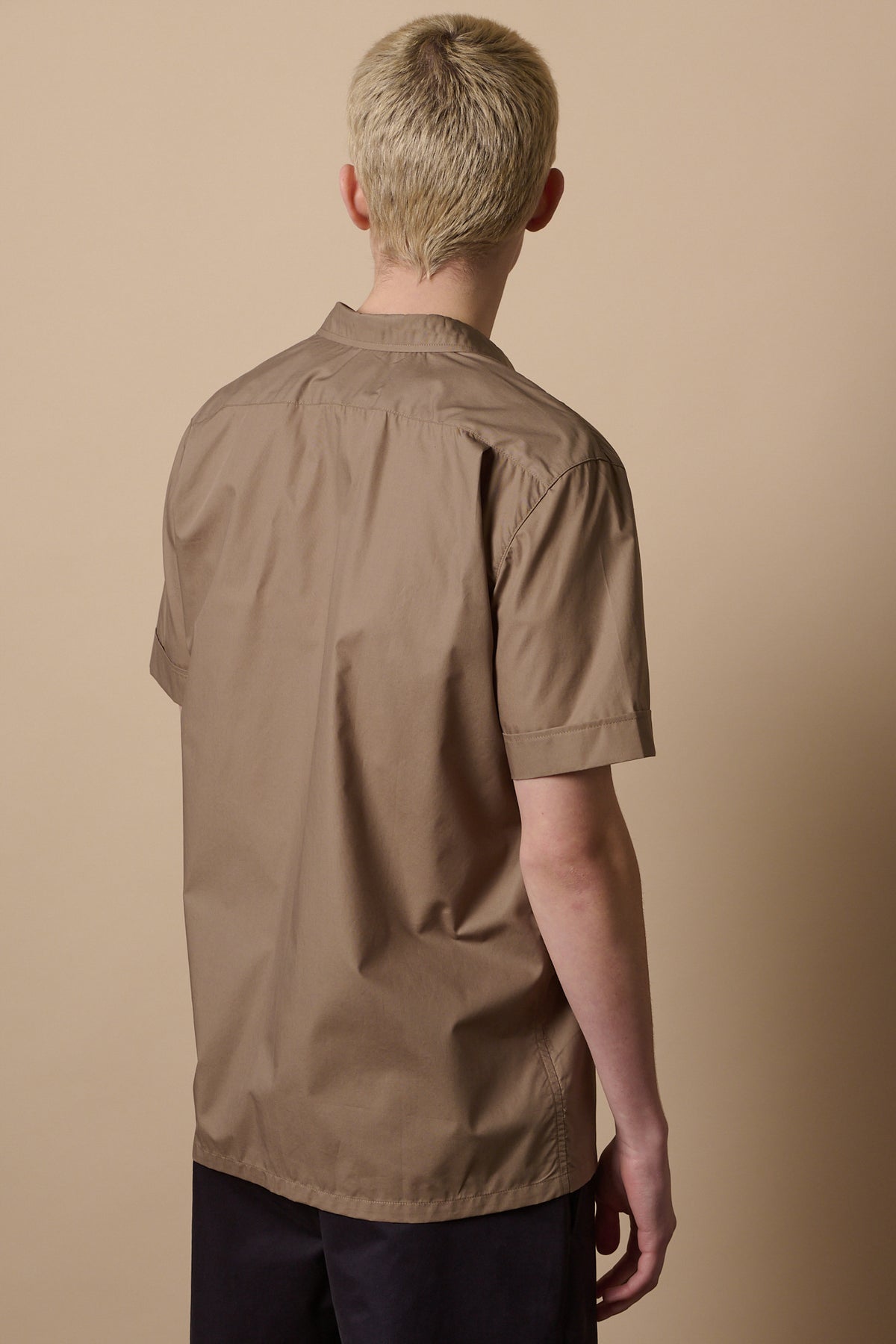 Thigh up image of the back of male with short blond hair wearing Tom short sleeve military shirt in khaki
