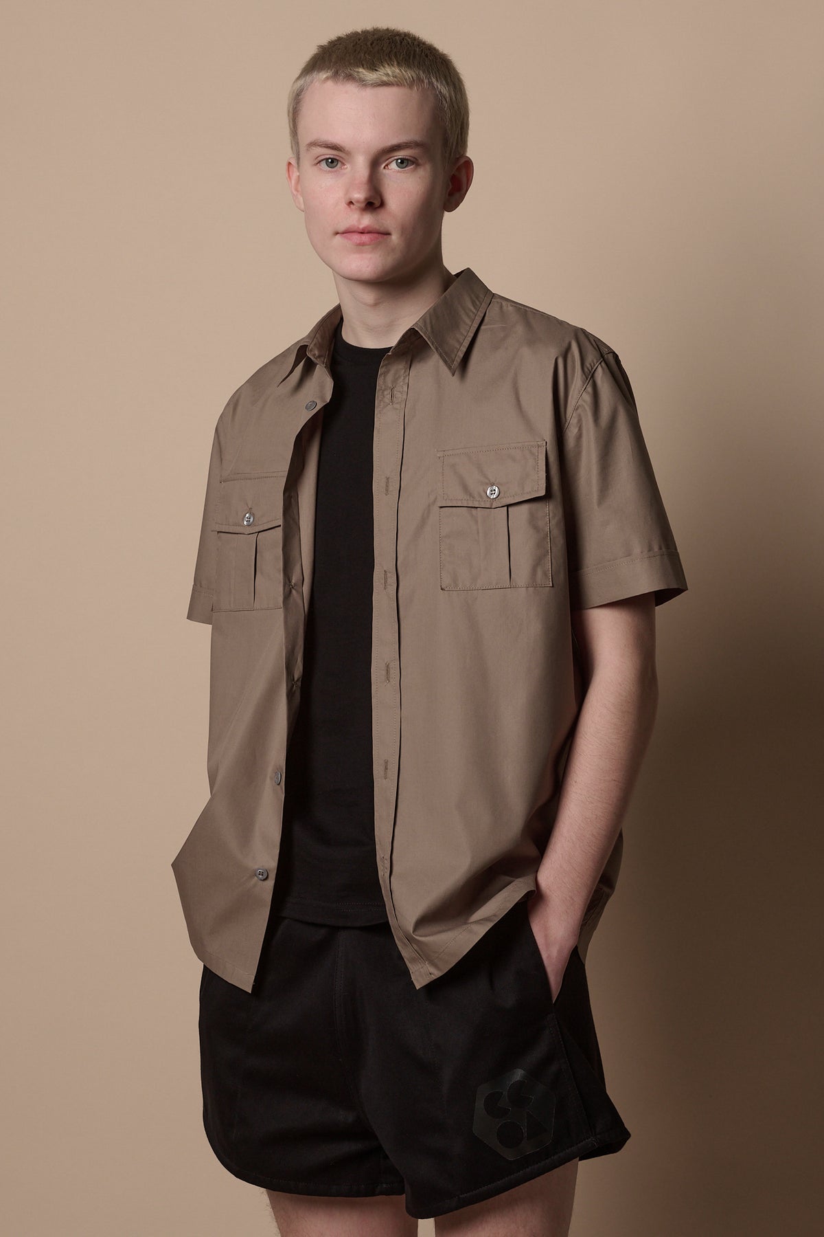 Thigh up front of male wearing Tom short sleeve military shirt in khaki