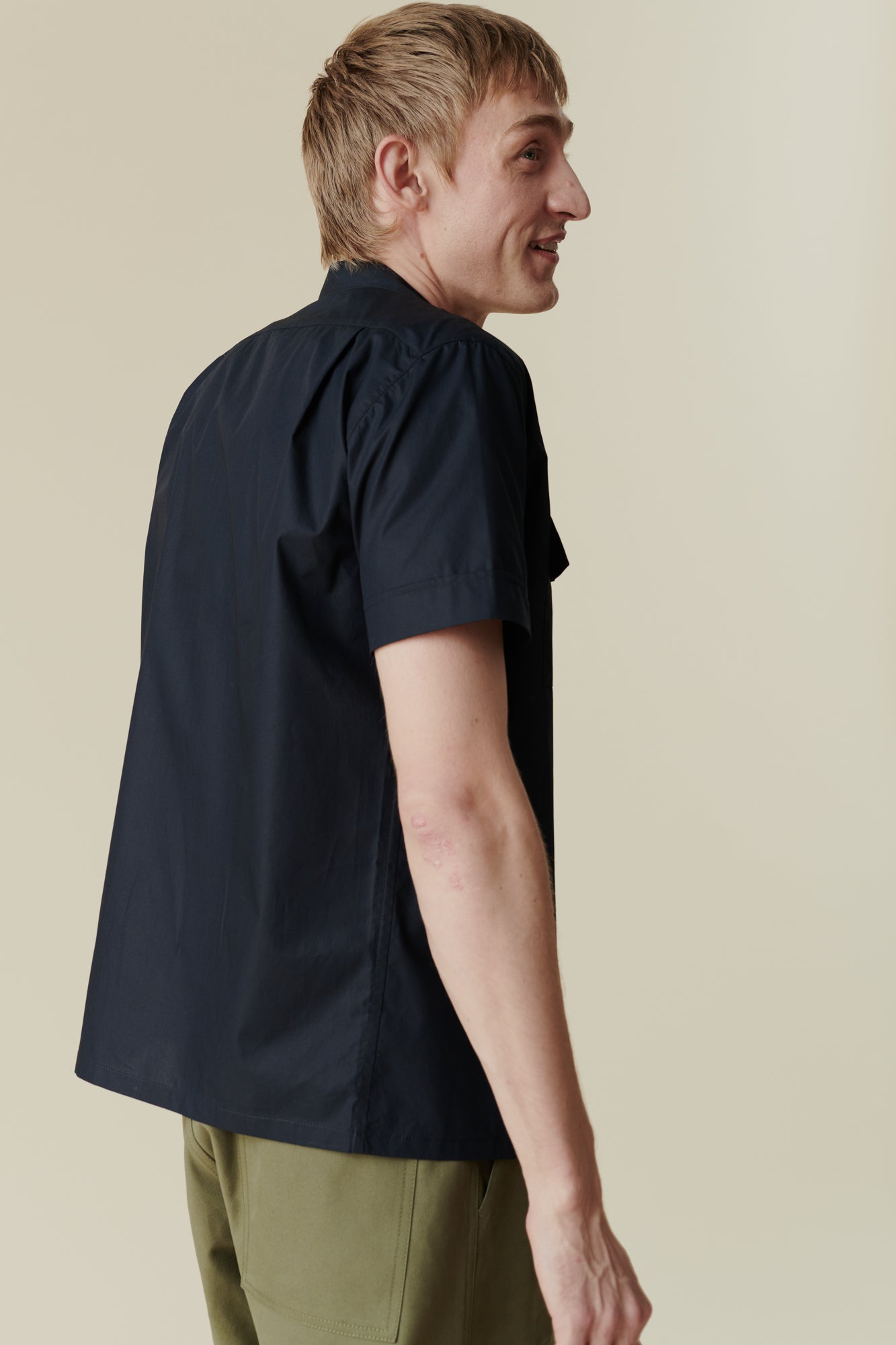 Back of white male wearing tom short sleeve military shirt with olive cameraman pants
