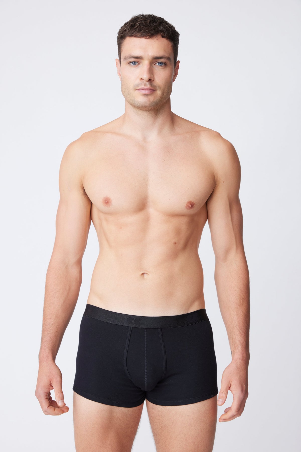 White male wearing black trunks