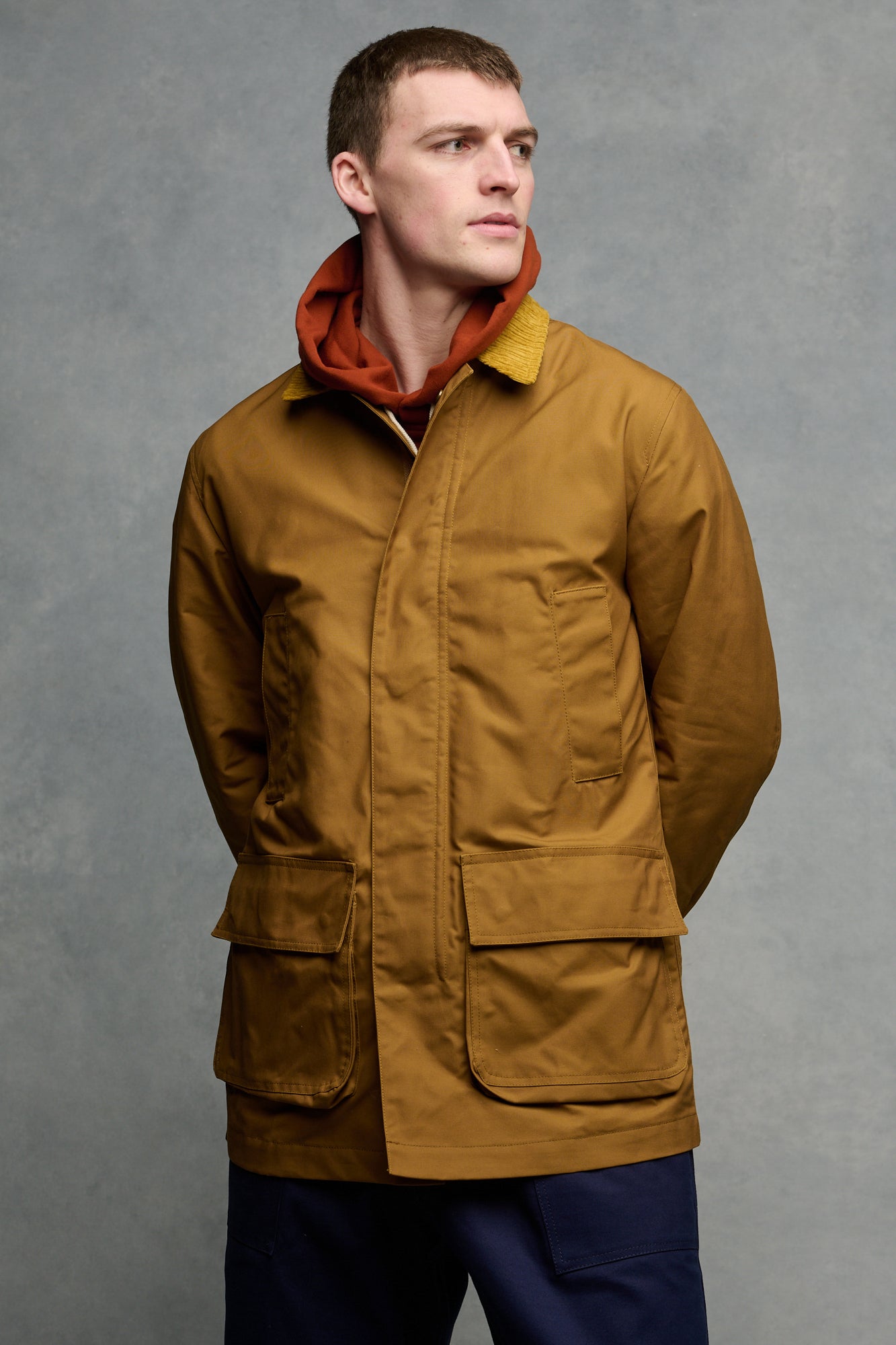 Man wearing a brown barn jacket holding a gardening tool.