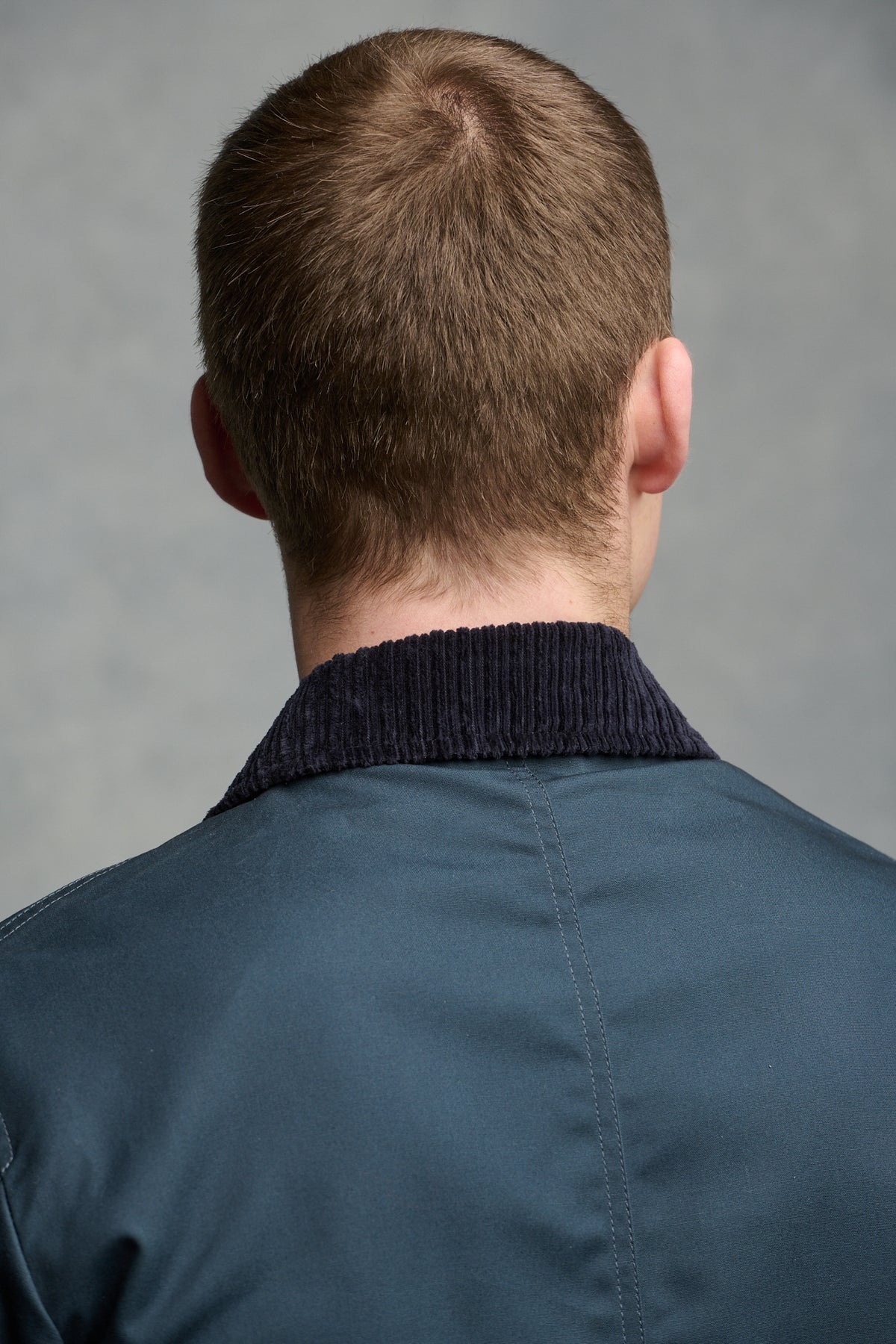 Close up of the back of shoulders of brunet male wearing barn jacketin navy, cord navy collar.