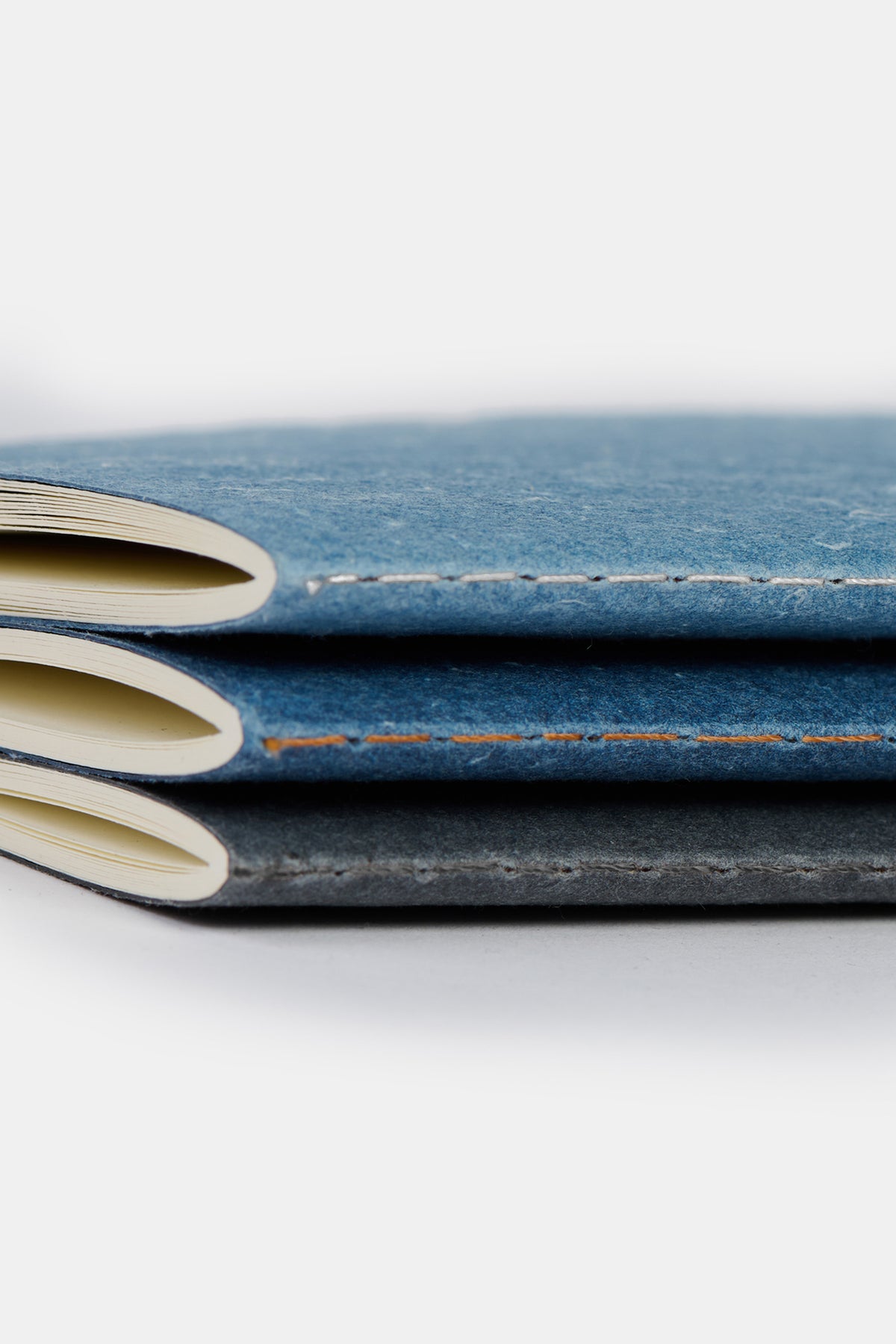 
            Close up of set of three notebooks made from recycled denim in black, indigo and blue