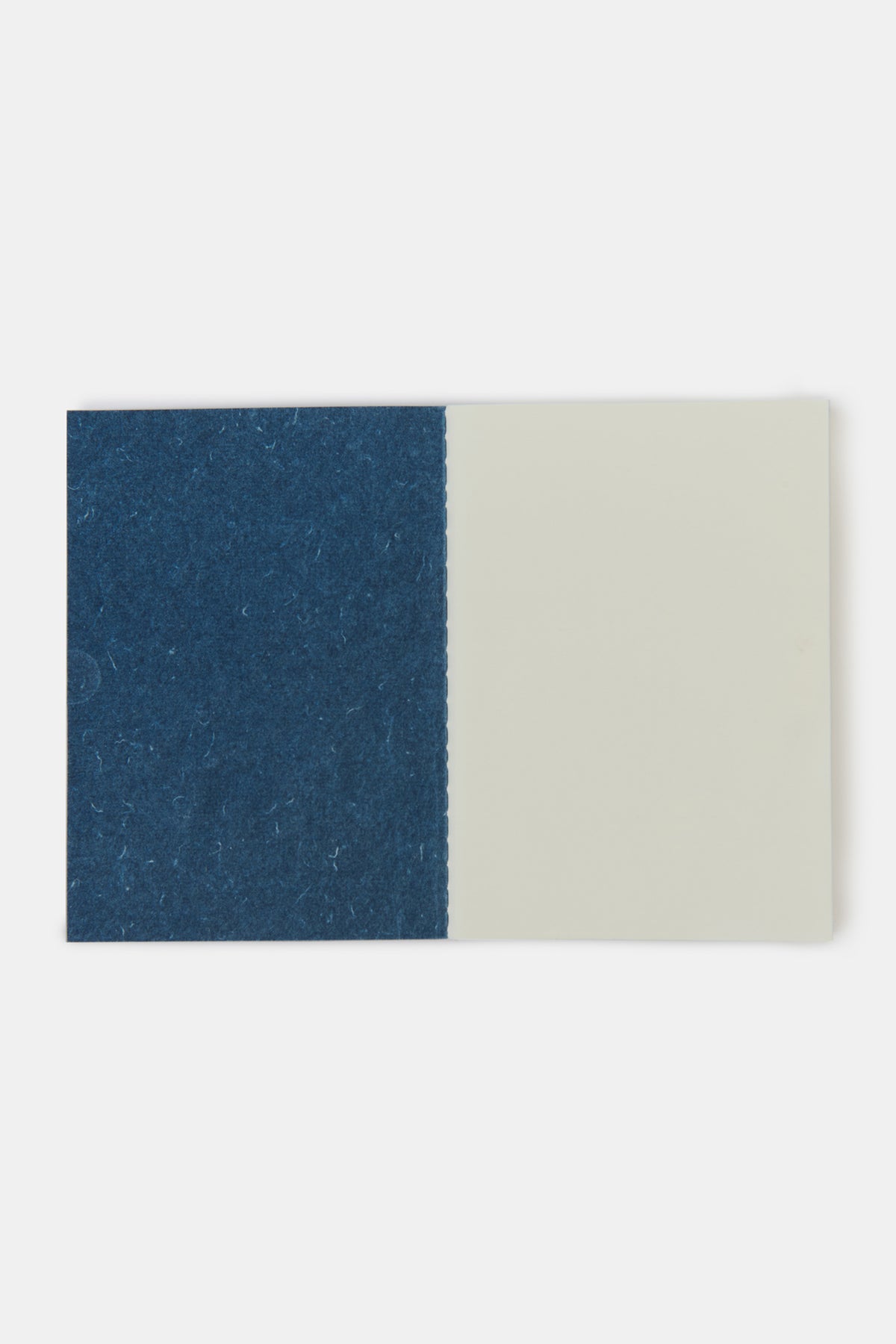 
            Community Clothing x Mark + Fold A6 notebook in indigo open to show the blank pages of the book