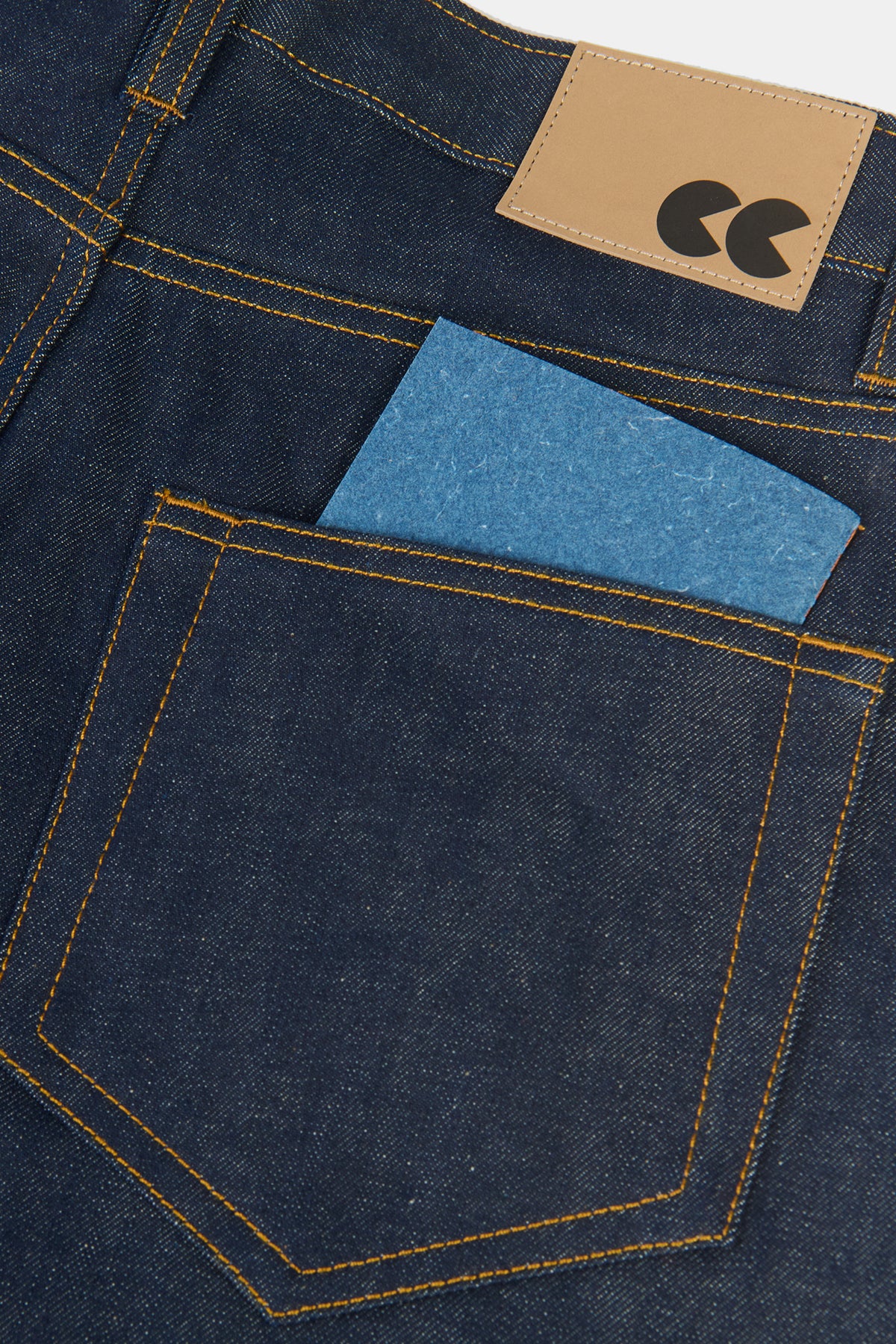 The front of Community Clothing x Mark + Fold A6 notebook in indigo coming out the back of indigo jeans pocket
