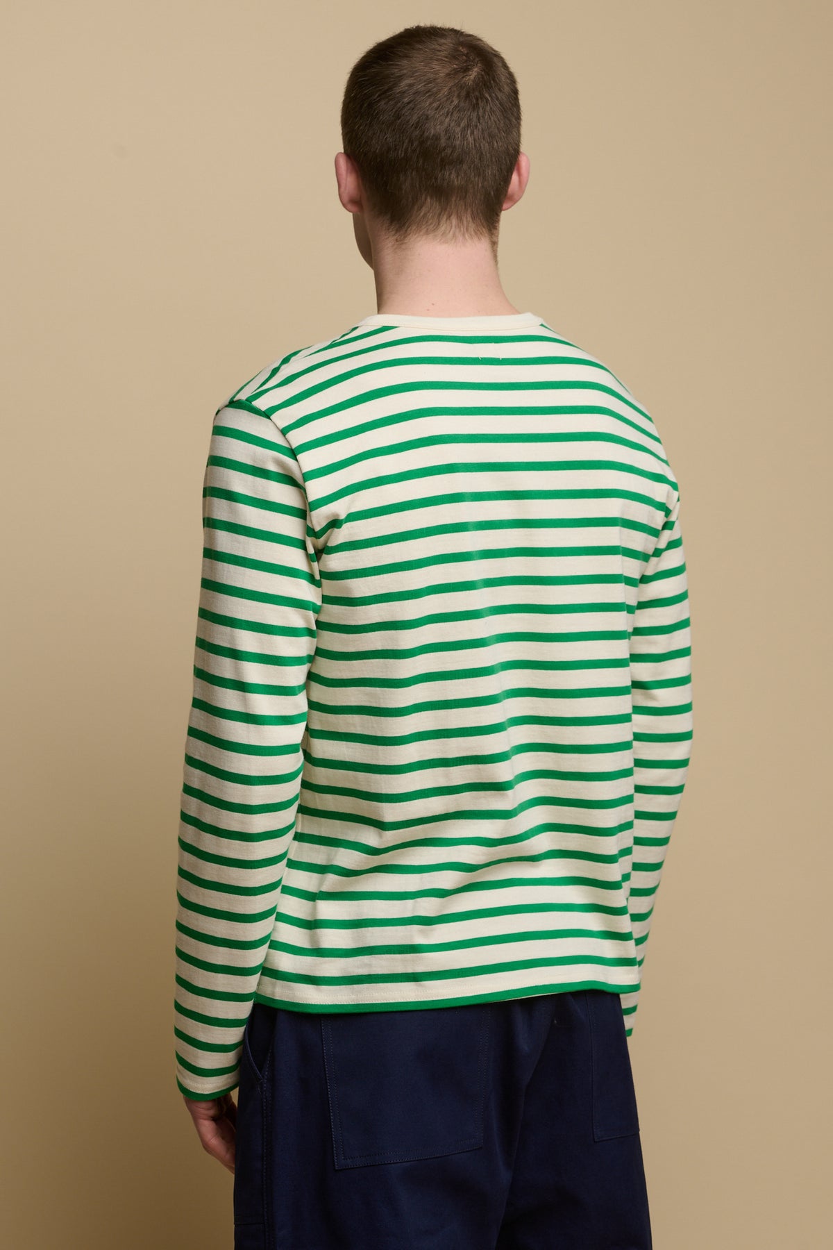 Thigh up image of the back of brunet male wearing Breton in ecru green