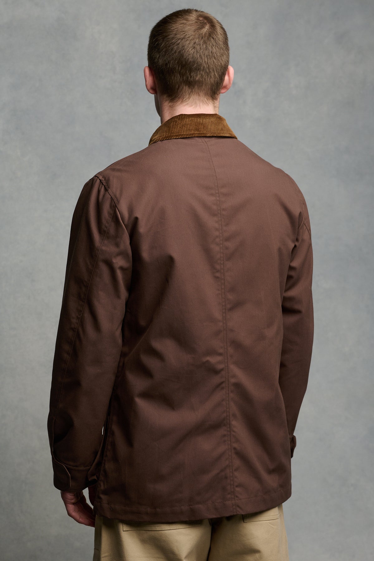 
            Thigh up image of the back of male wearing car coat in brown with brown coat collar